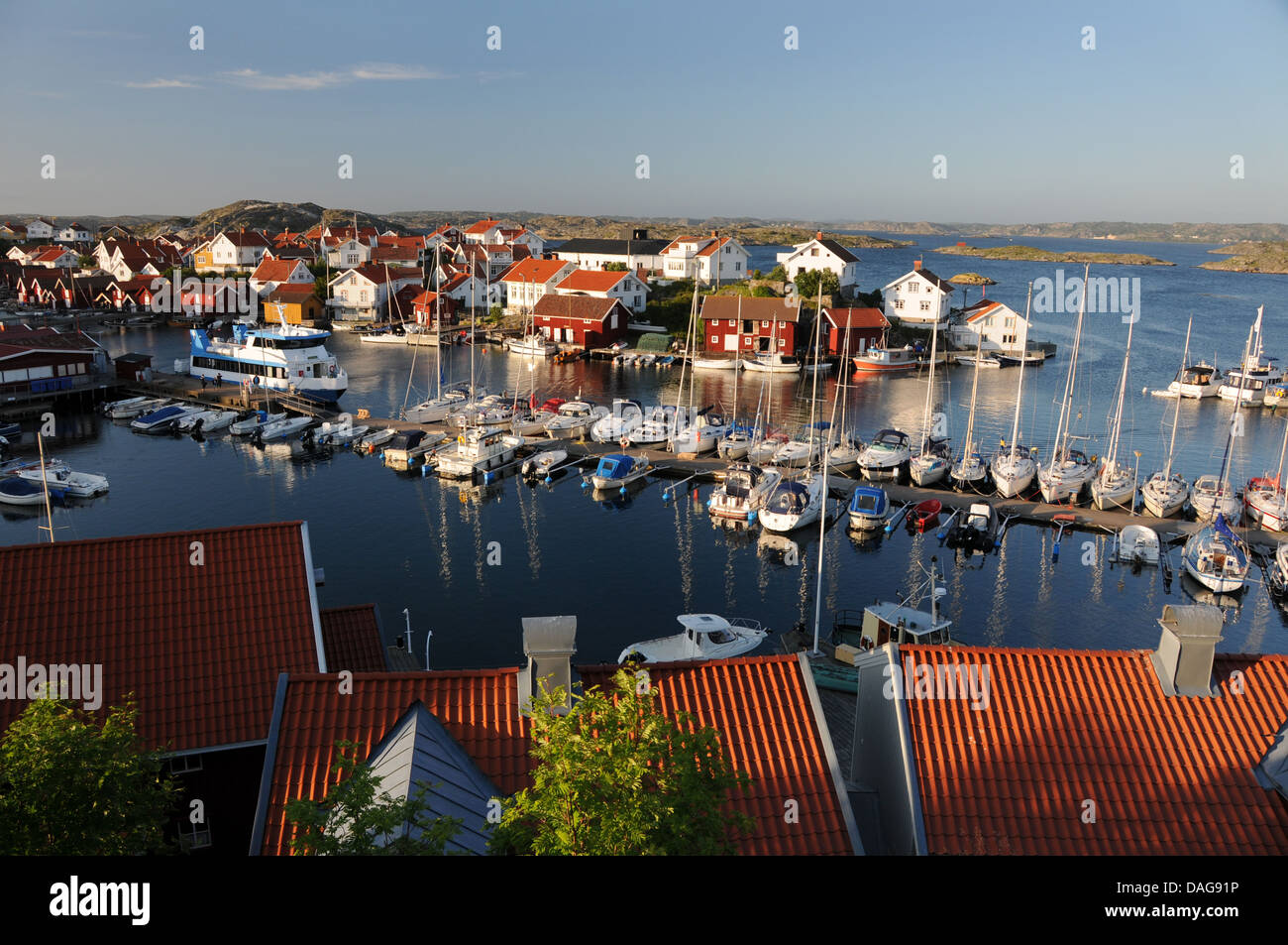 Small harbor filled with boats, yachts, and colorful homes on island of Gullholmen in Bohuslän on West Coast of Sweden Stock Photo