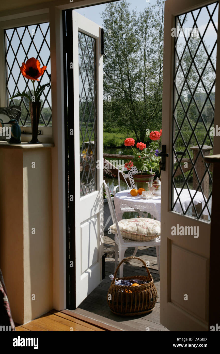 Lattice glass panels in double doors open to balcony with white chair and  table and view of country garden in summer Stock Photo - Alamy