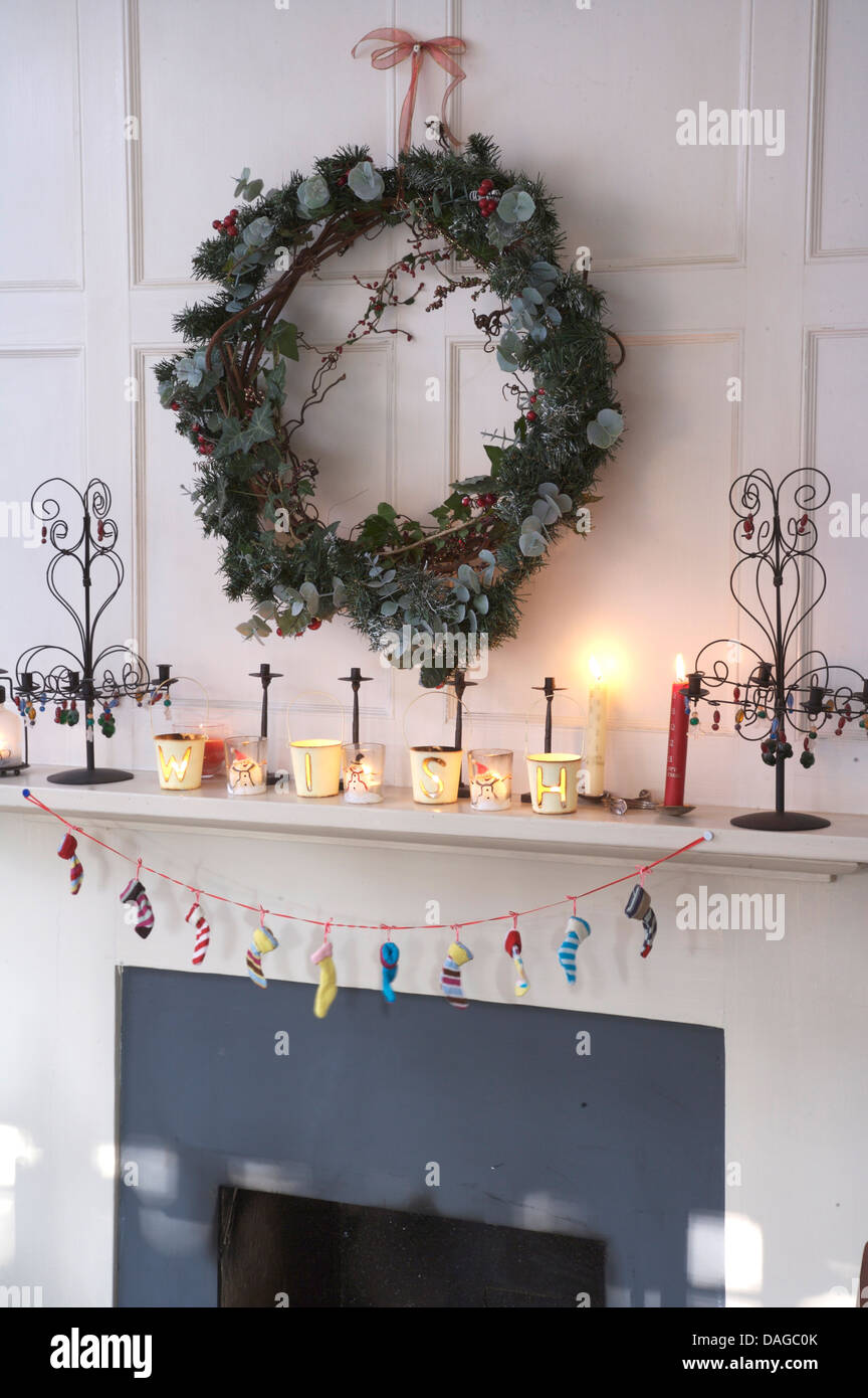 Ivy and conifer wreath above fireplace decorated for Christmas with lit