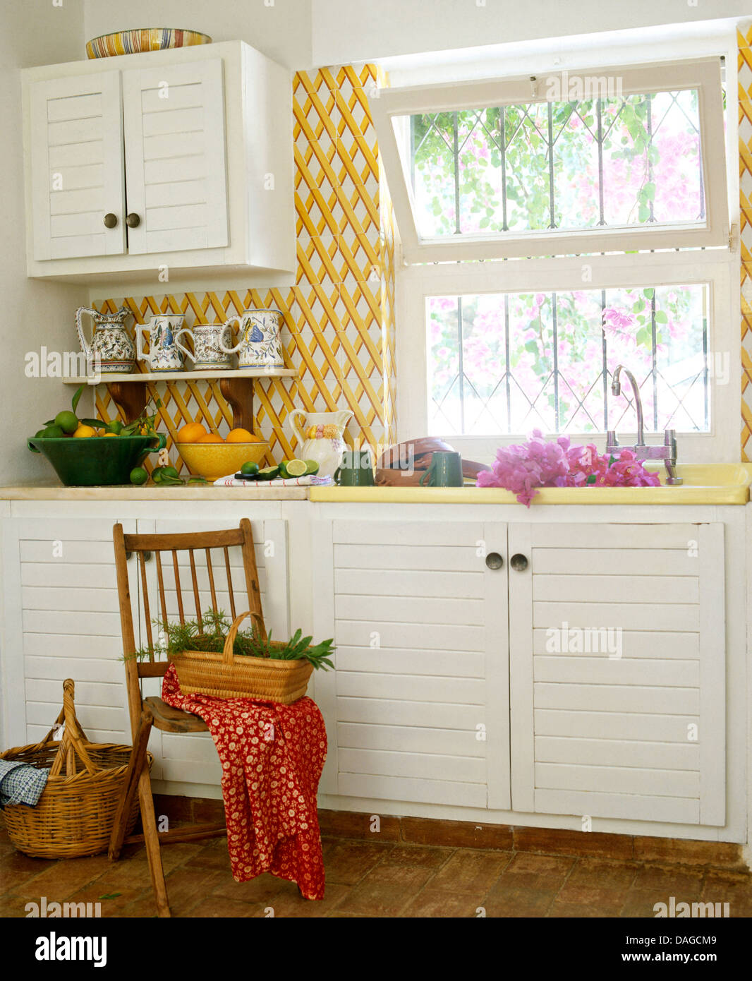 Yellow trellis wallpaper beside window in coastal kitchen with simple  wooden chair beside sink Stock Photo - Alamy