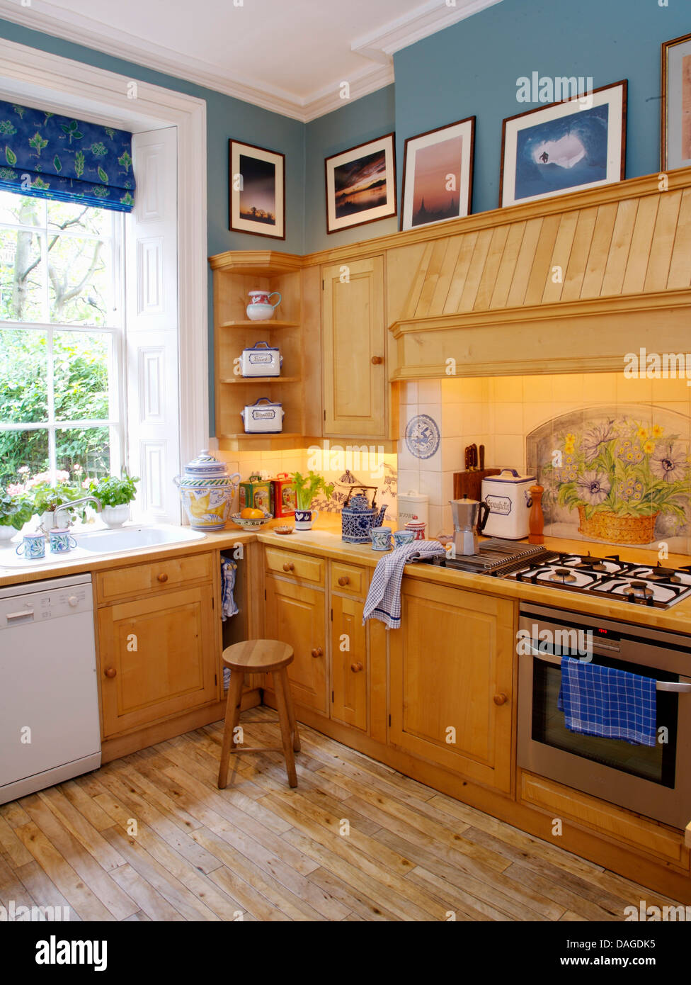Pale wood fitted units and wooden floor in blue kitchen with lighting ...