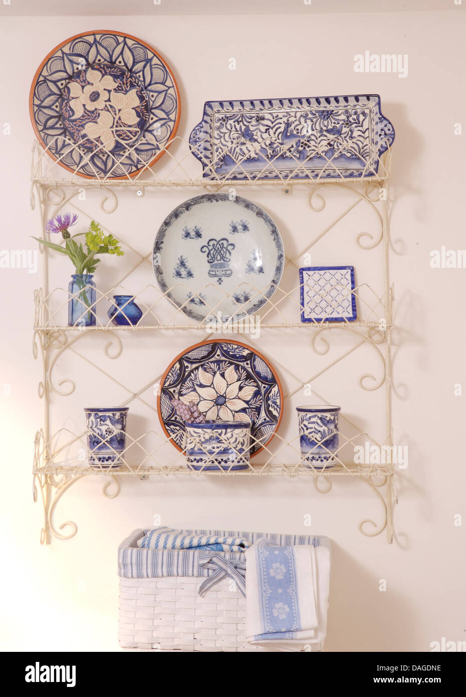 Collection of blue+white plates and china displayed in white wire work shelf unit Stock Photo