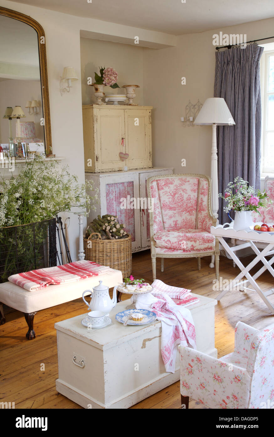 Coffee pot on white painted chest in cottage living room with pink Toile de Jouy chair and floral chair Stock Photo