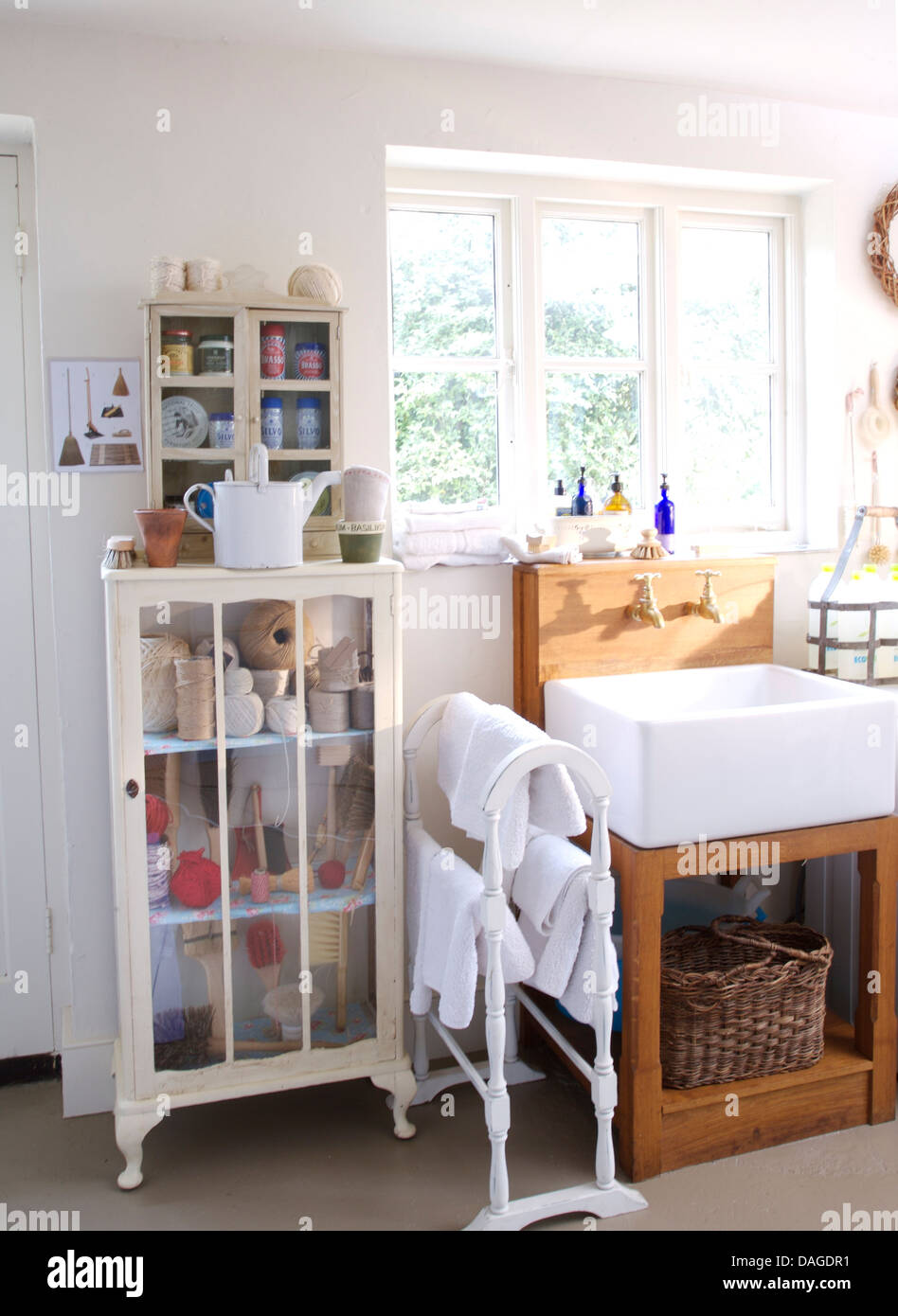 Small glass fronted cupboard and white towel rail with white towels beside Belfast sink in country bathroom Stock Photo Alamy