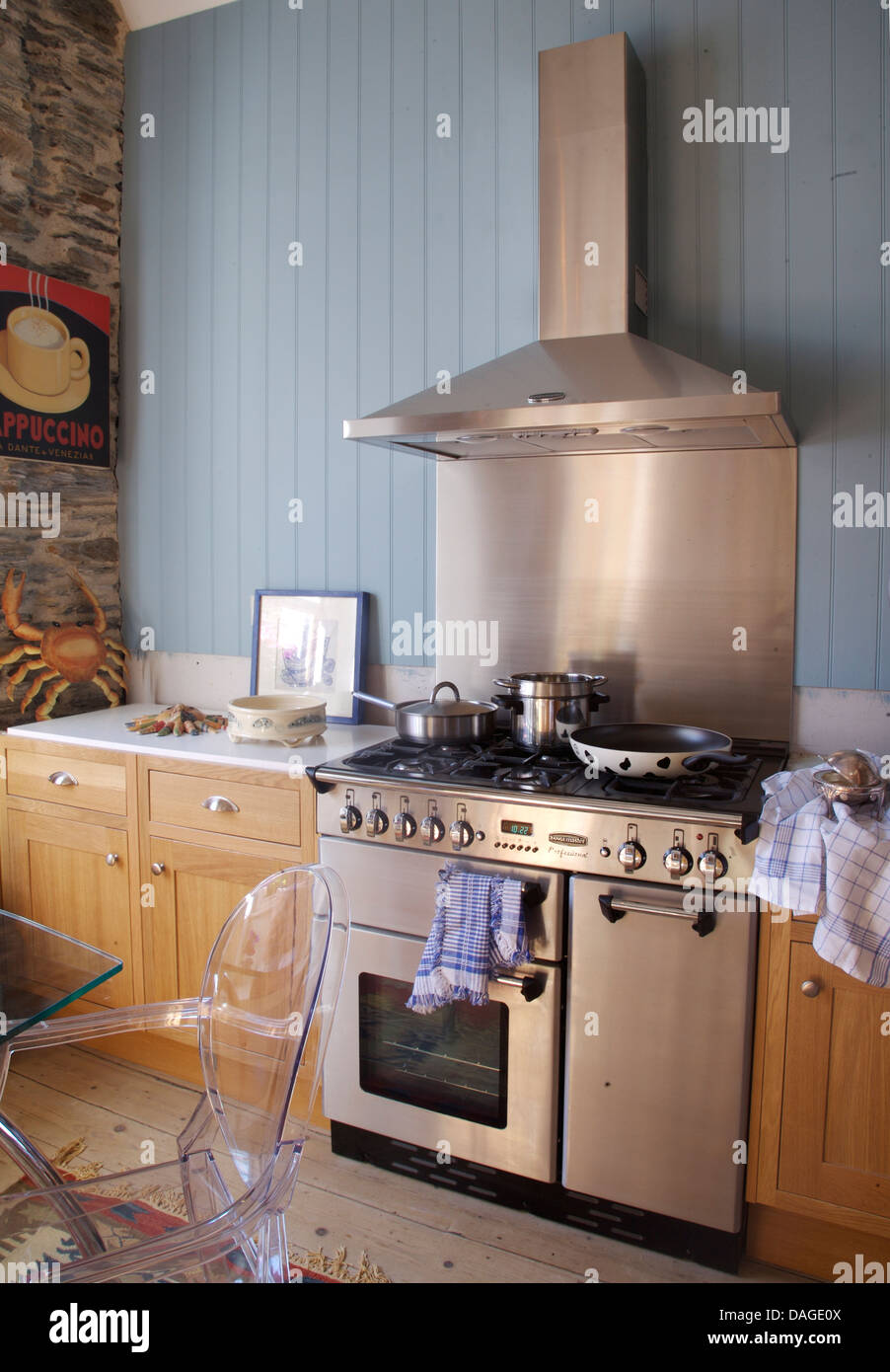 Stainless steel splash back cooker hood above range oven and cooker hood in country kitchen with blue tongue+groove paneling Stock Photo