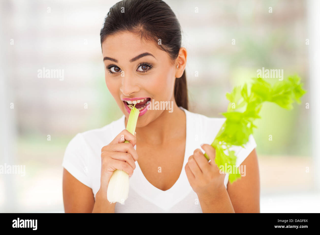 beautiful young woman biting fresh celery stick Stock Photo