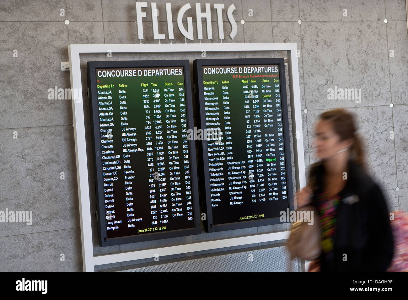 A woman walks by the flights departures screen at the General Mitchell International Airport in Milwaukee Stock Photo