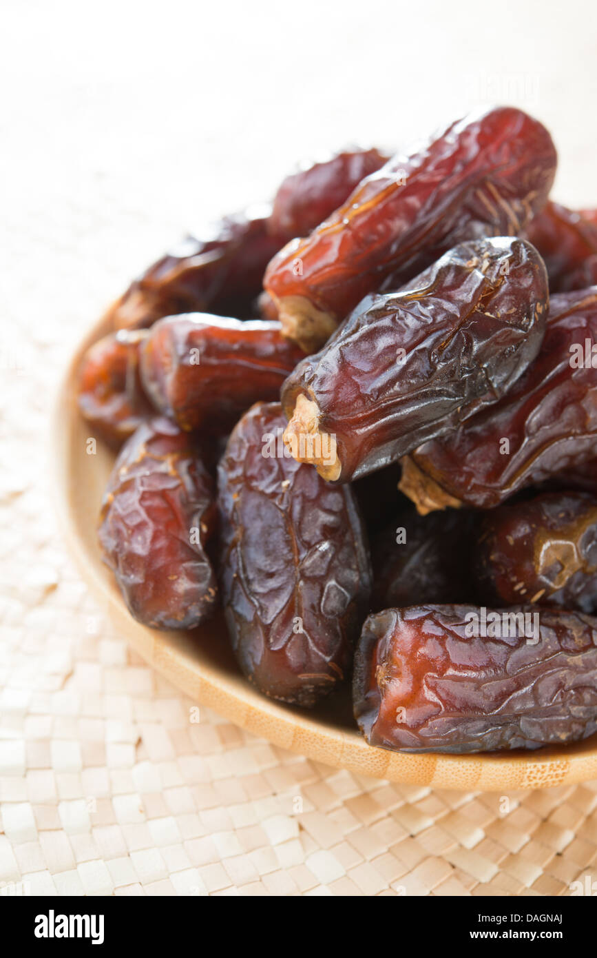 Dates fruit. Pile of fresh dried date fruits in a wooden plate. Stock Photo