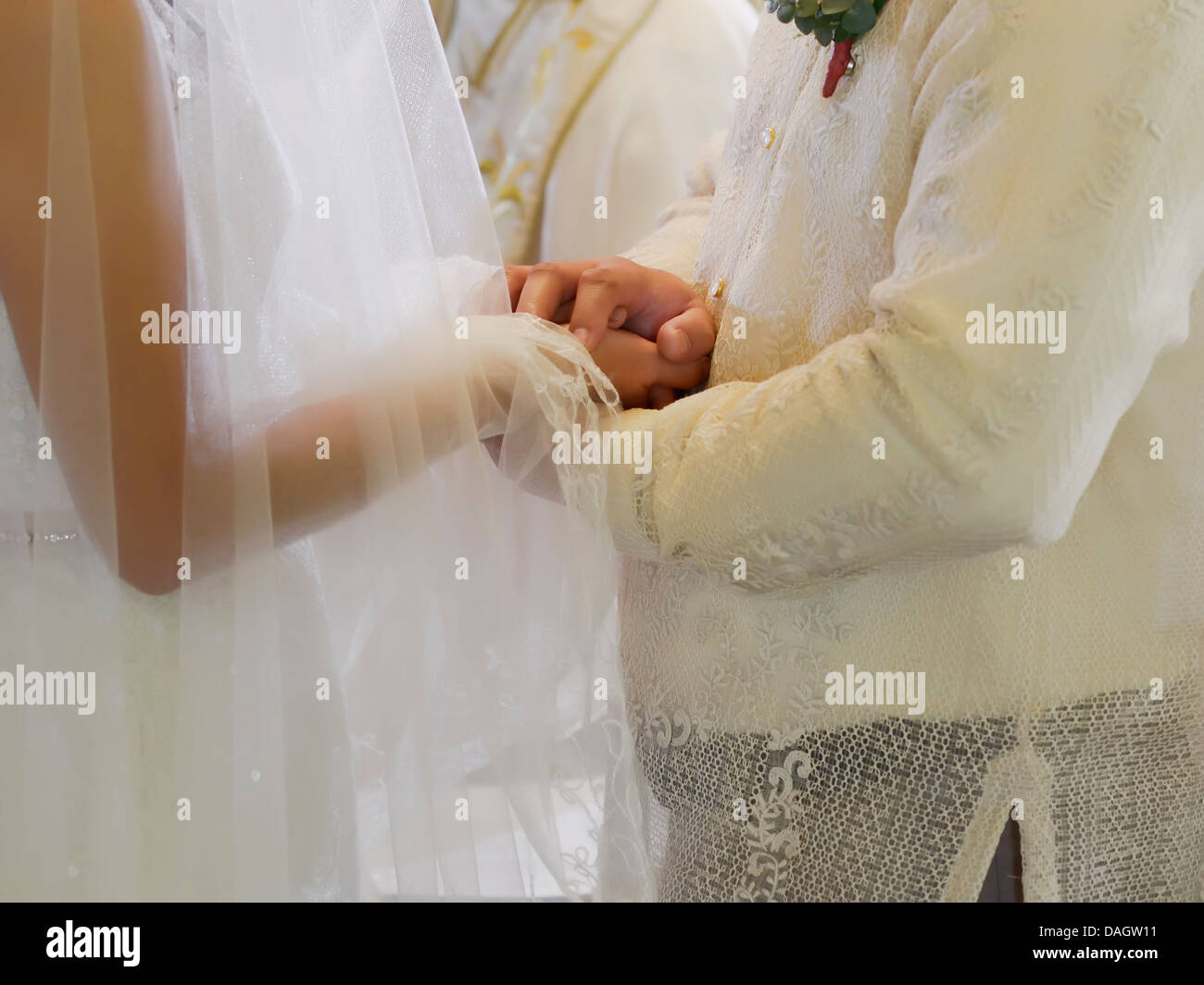 Closeup of bride and groom holding hands during a wedding ceremony Stock Photo