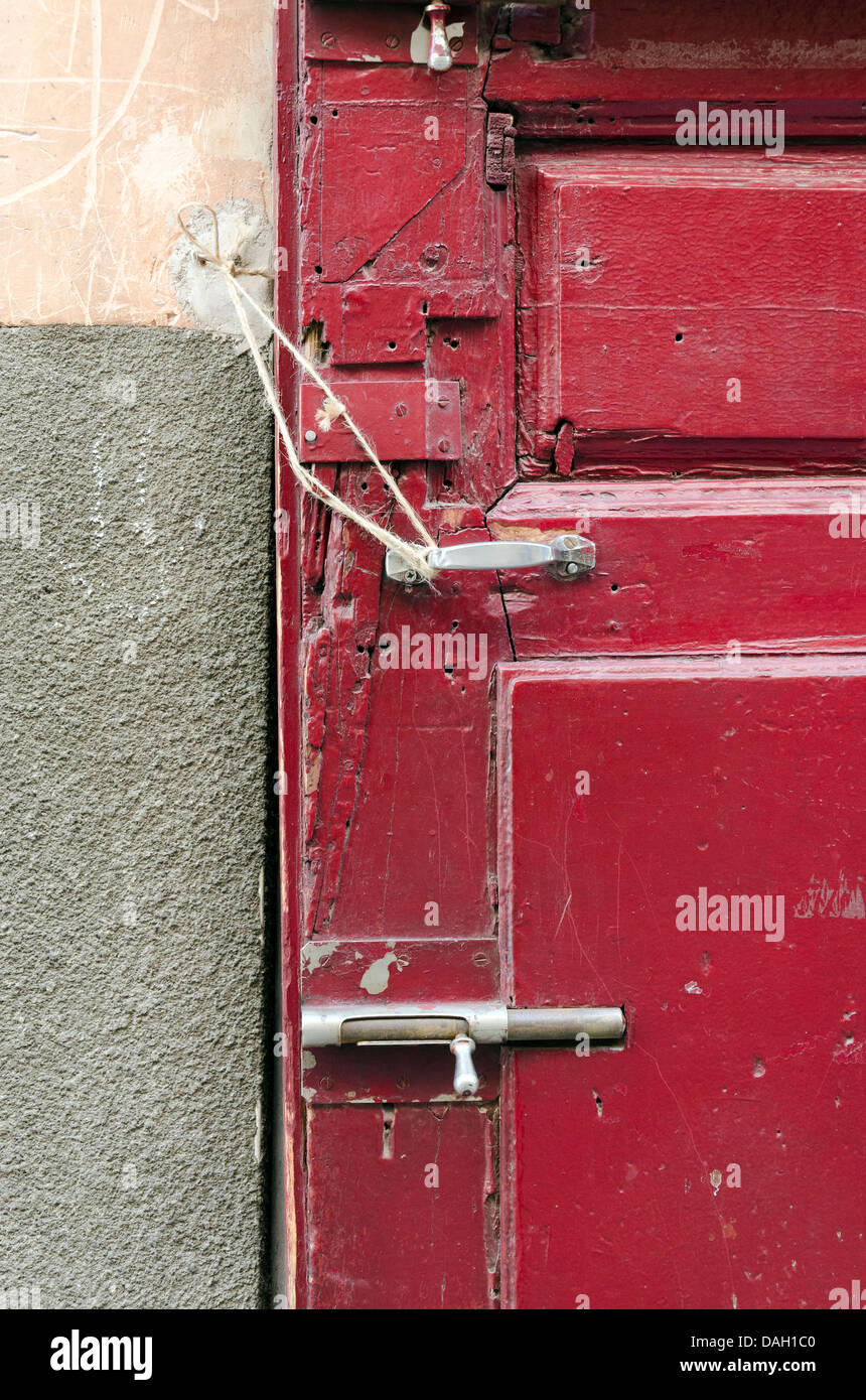 An old red door with a lock wich is complete disorder Stock Photo
