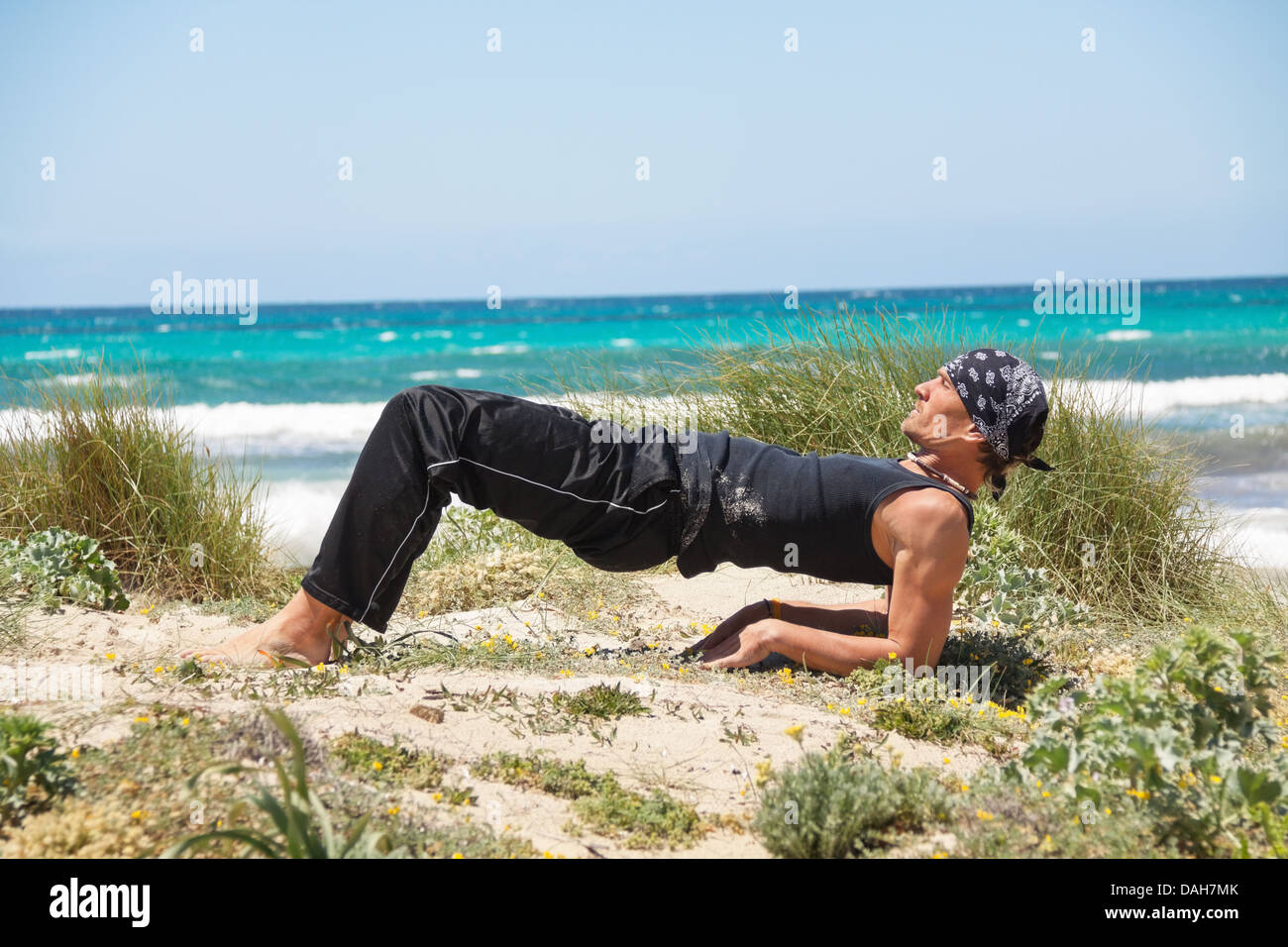 adult healthy man doing pilates yoga exercise on beach in summer Stock Photo