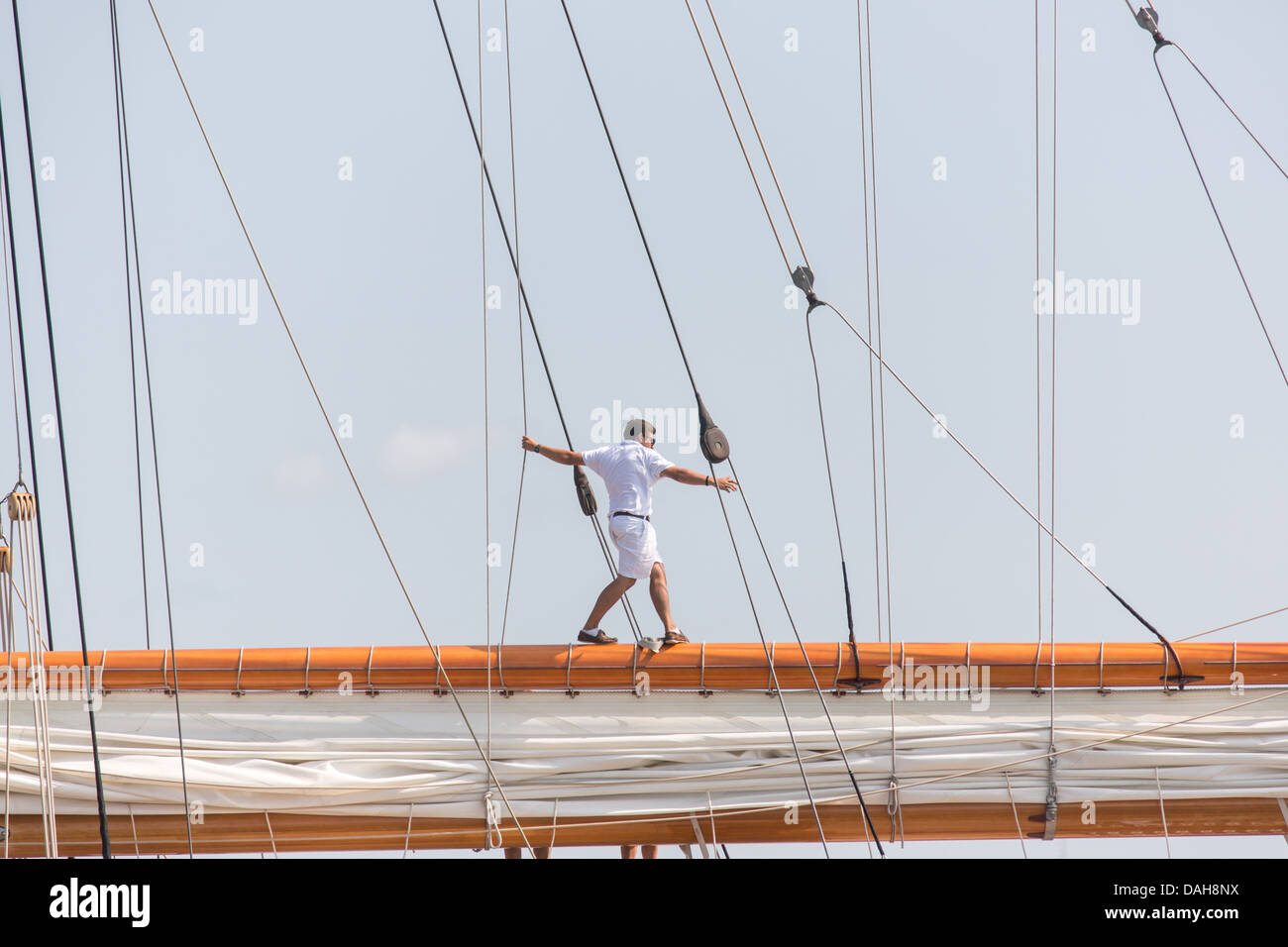 A deck hand walks on the main gaff spar on the 196-foot sailing yacht Germania Nova as it sails Charleston Harbor June 26, 2013 in Charleston, South Carolina. Stock Photo