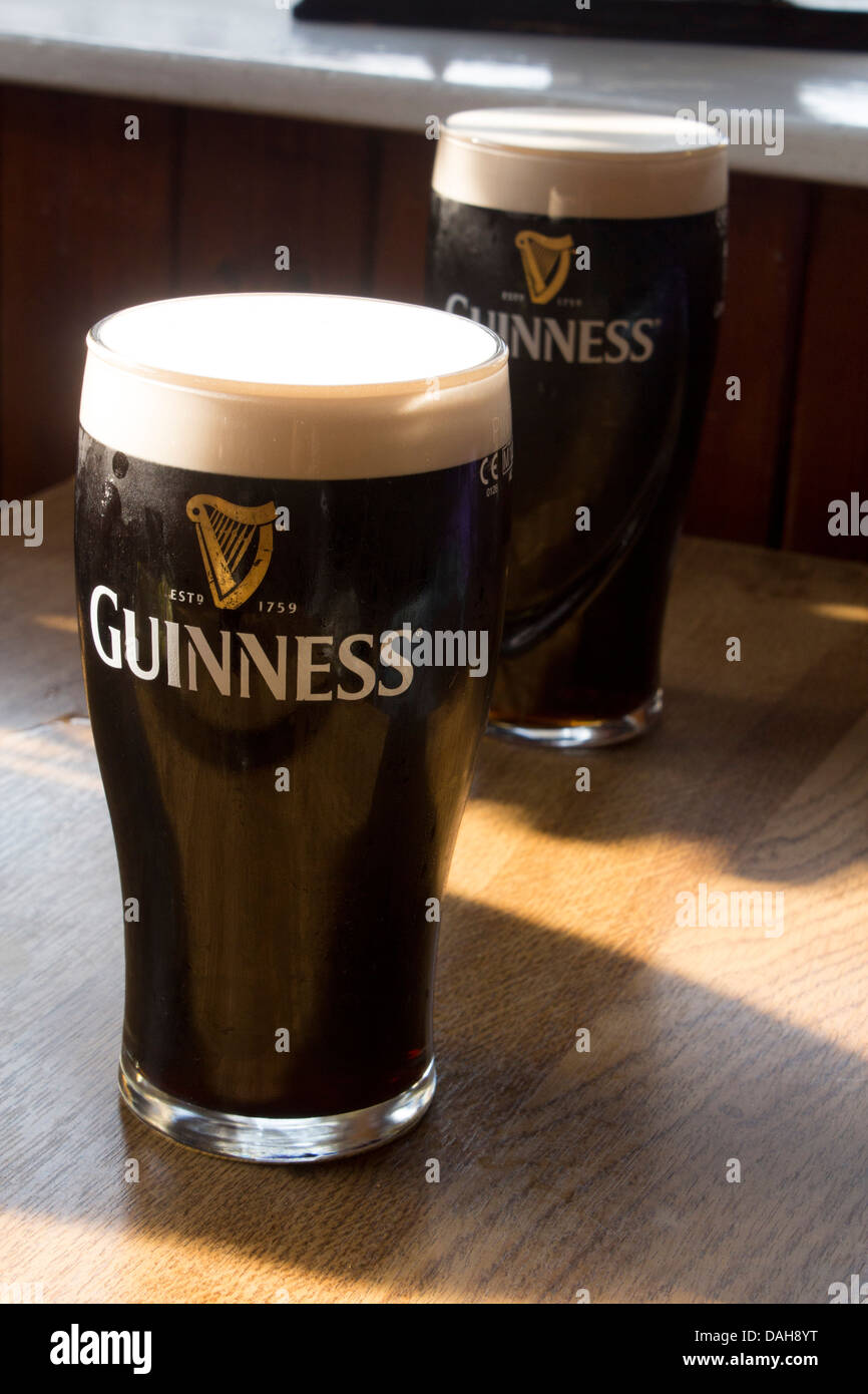 Two pints of Guinness on a table in a pub in Ireland Stock Photo