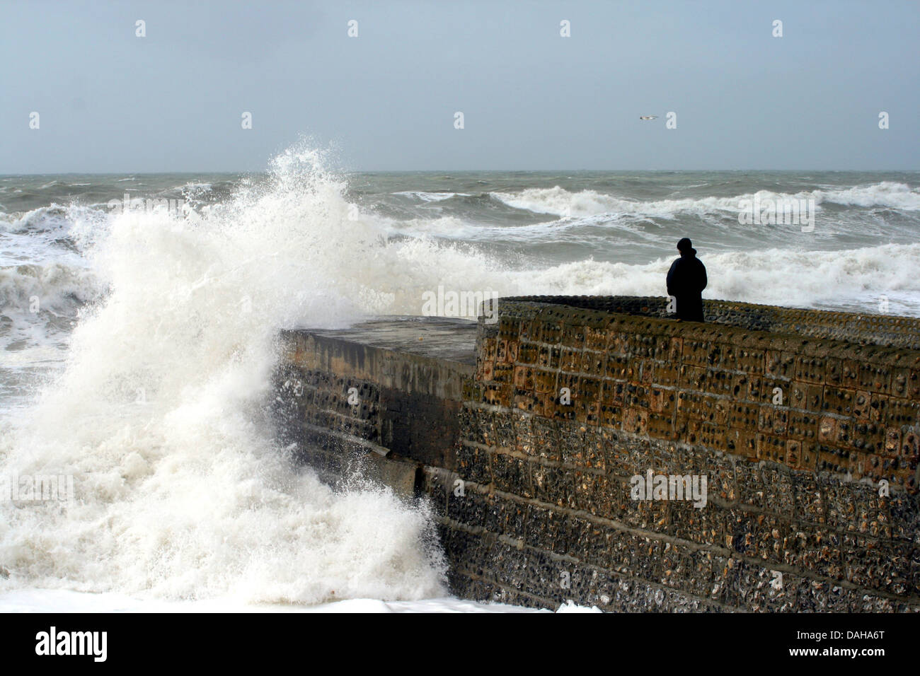 A Lone figure looks out to sea during a storm. Stock Photo
