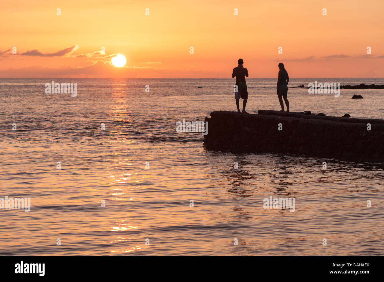 Couple watch sunset at Anaehoomalu Beach on the Big Island of Hawaii Stock Photo