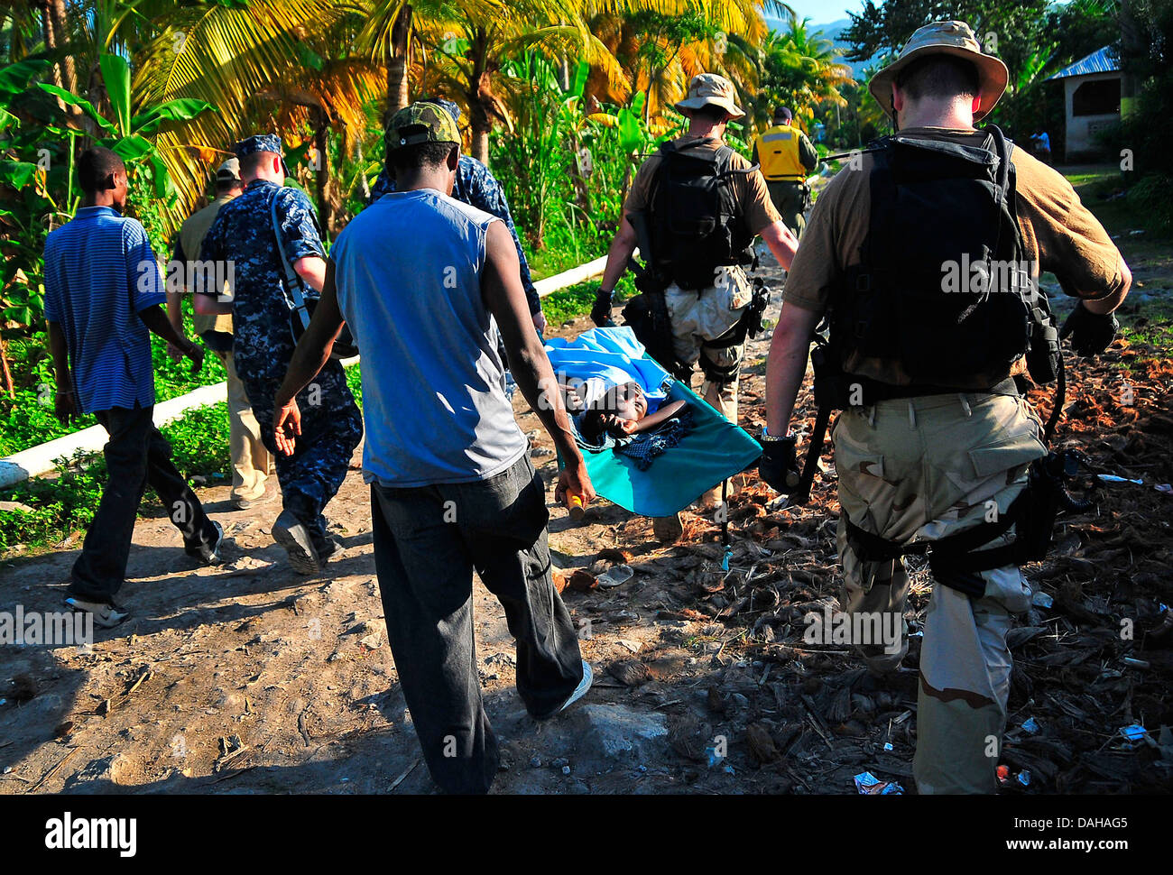 US sailors carry an injured Haitian girl for a medical evacuation in the aftermath of a massive earthquake that killed 220,000 people January 22, 2010 in Port-au-Prince, Haiti. Stock Photo