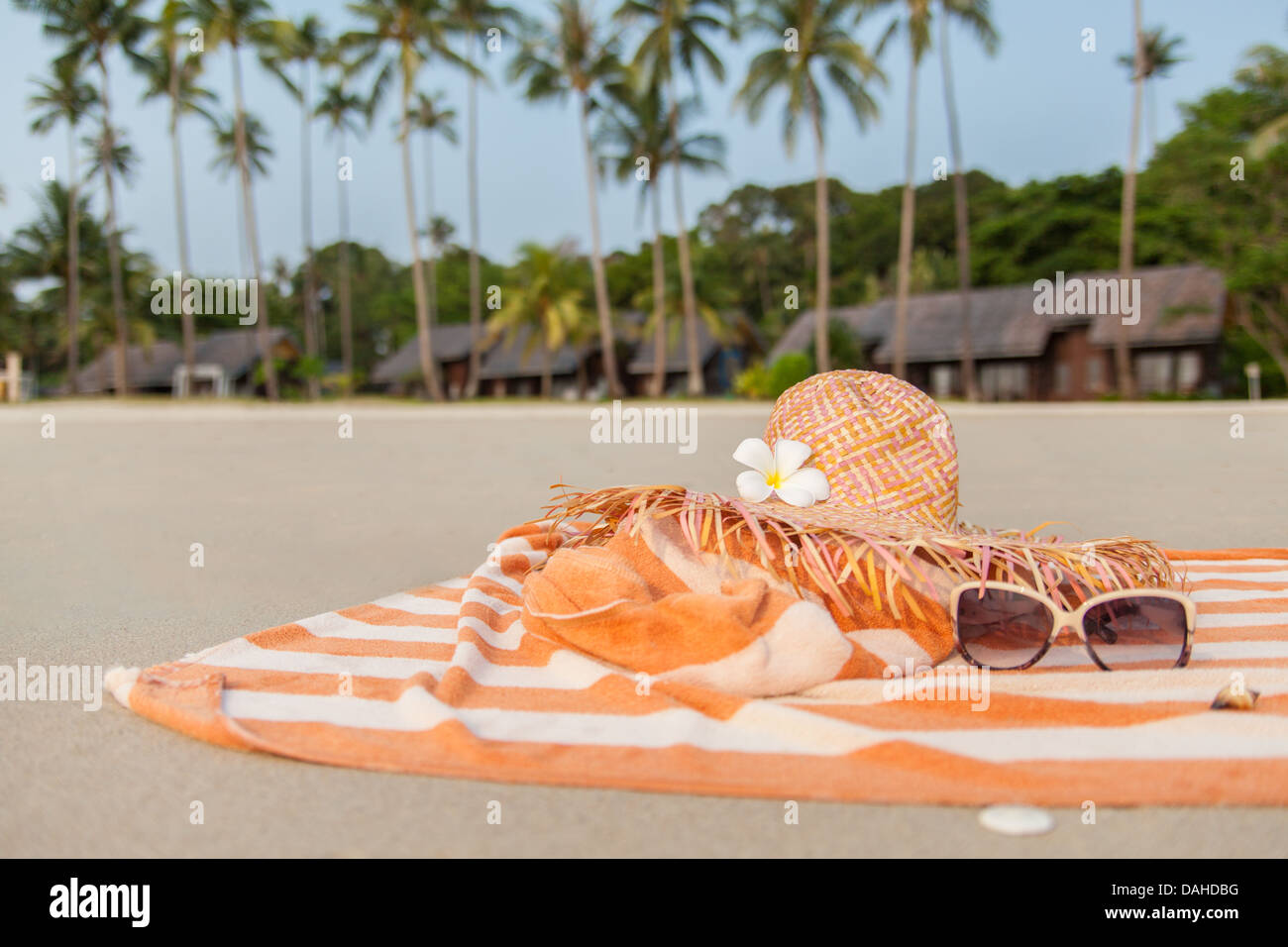 beach hat and flower on towel in the sand with resorts in the ...