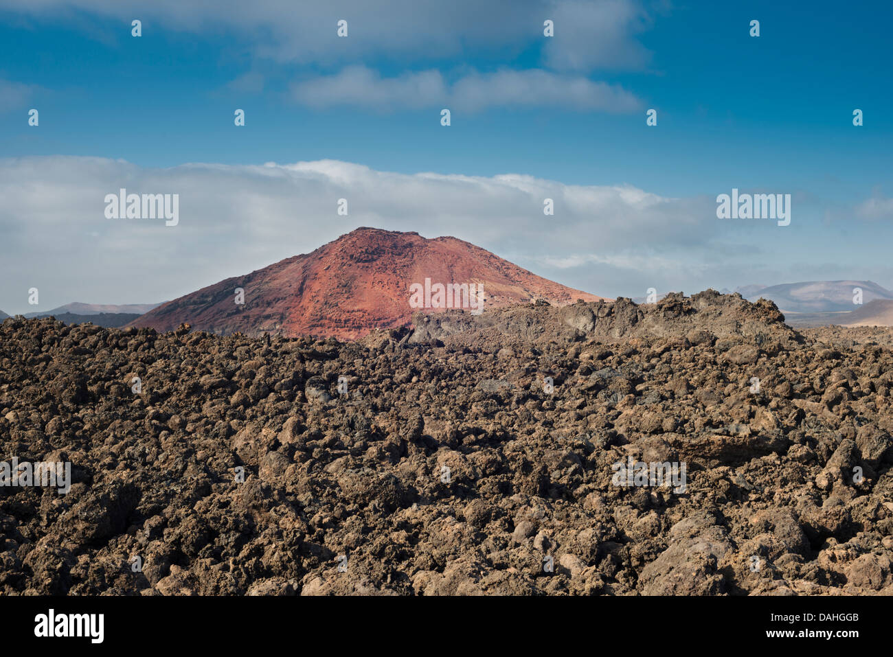 Aa lava field from the historic eruptions on Lanzarote with Montana Bermeja, a young, oxidised, red, strombolian volcanic cone in the background Stock Photo