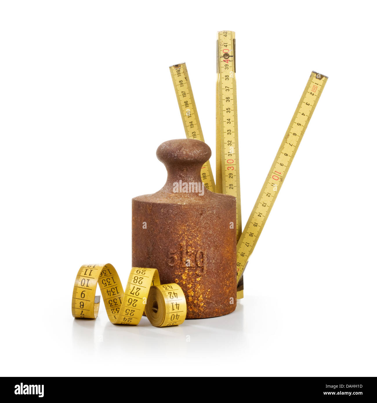Old rusty weight, yellow tape measure and yardstick on white background Stock Photo