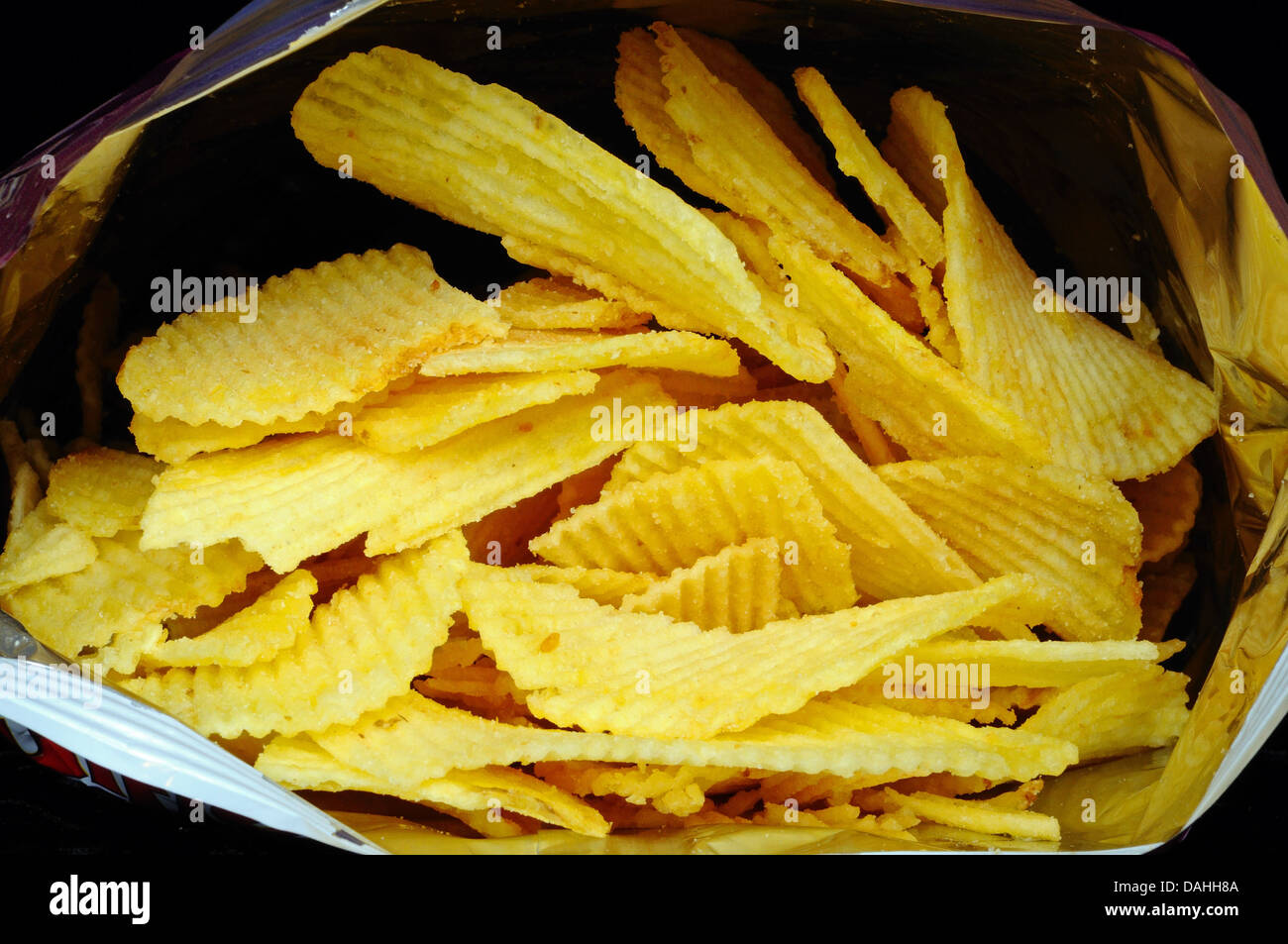 Looking into an open packet of crinkle cut crisps. Stock Photo