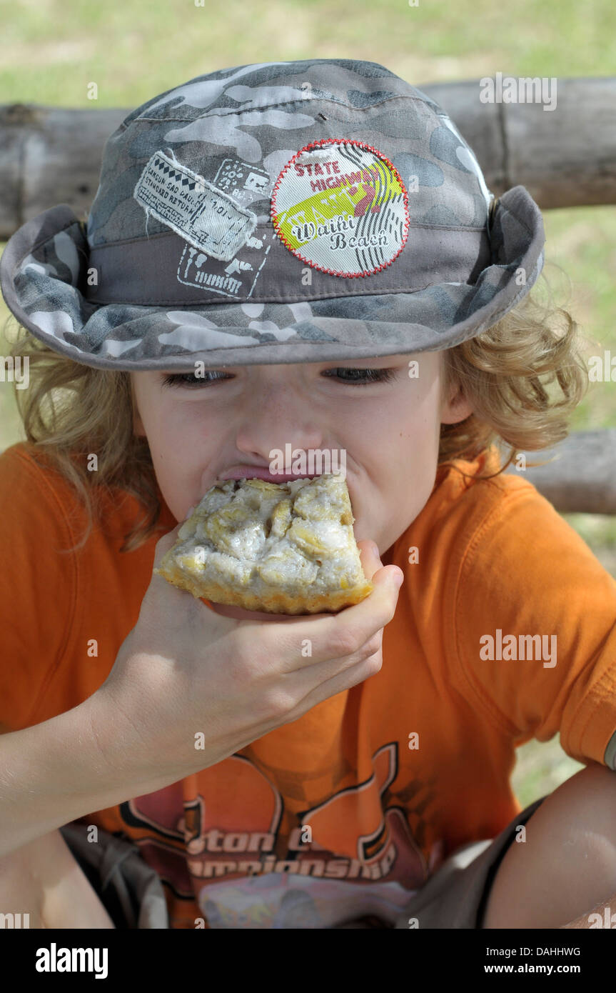 Boy with camouflage hat eating banana pie Stock Photo Alamy