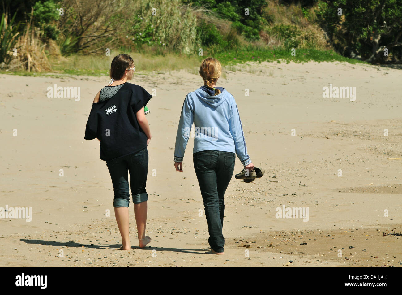 Two young women enjoying walk on sandy beach Stock Photo - Alamy