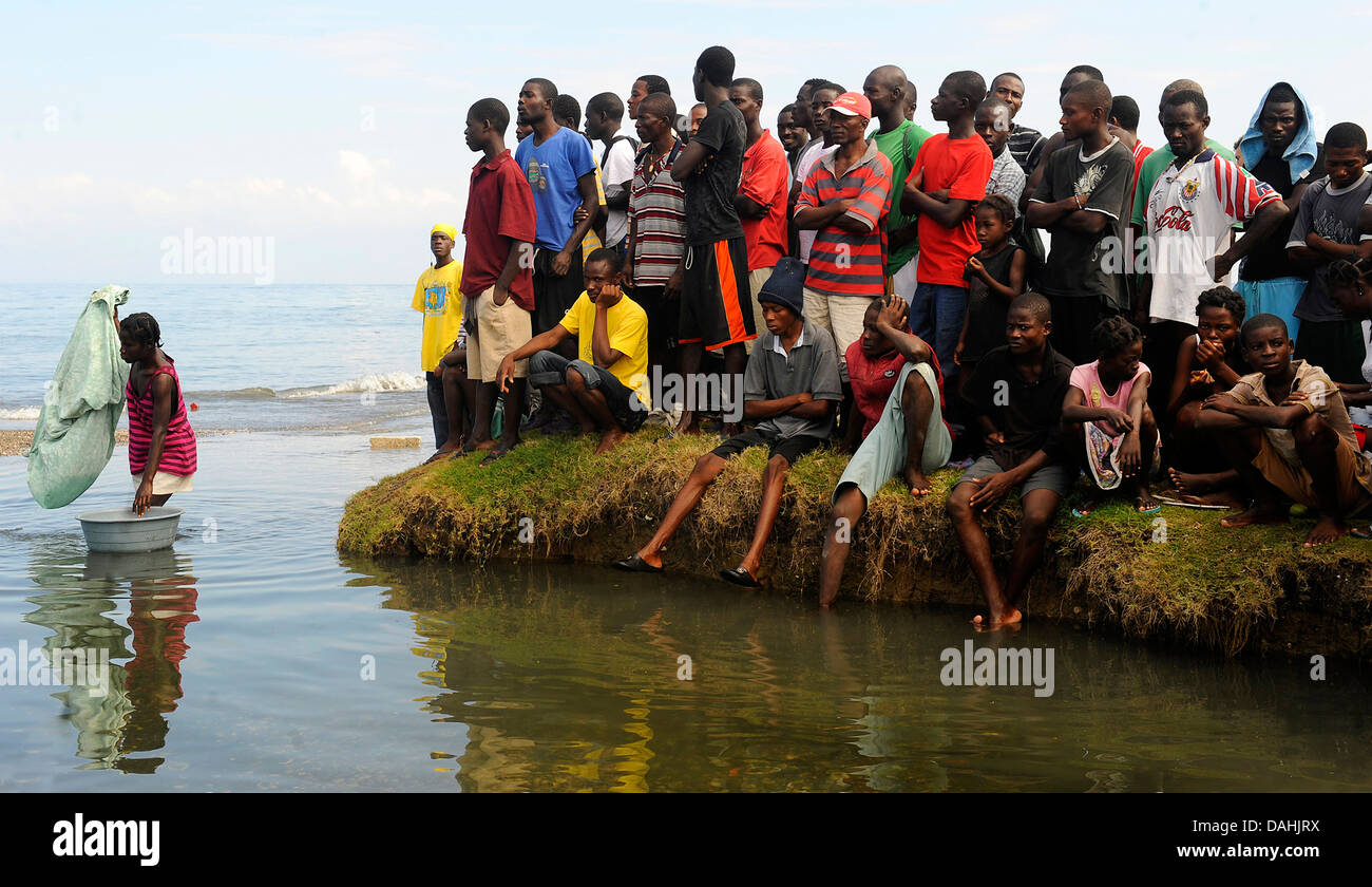 Haitians watch from the shore as US Navy landing craft arrive carrying emergency aid after a 7.0 magnitude earthquake devastated the country and killed 220,000 people January 19, 2010 in Bonel, Haiti. Stock Photo
