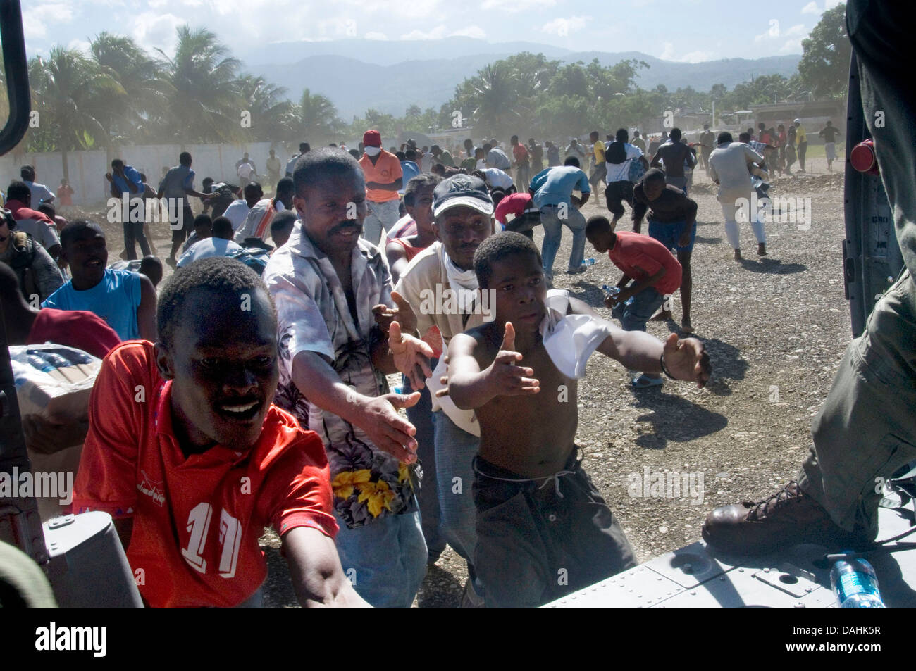 Haitians jostle for food rations as a US Navy helicopter unloads aid in the aftermath of the 7.0 magnitude earthquake that killed 220,000 people January 16, 2010 in Port-au-Prince, Haiti. Stock Photo