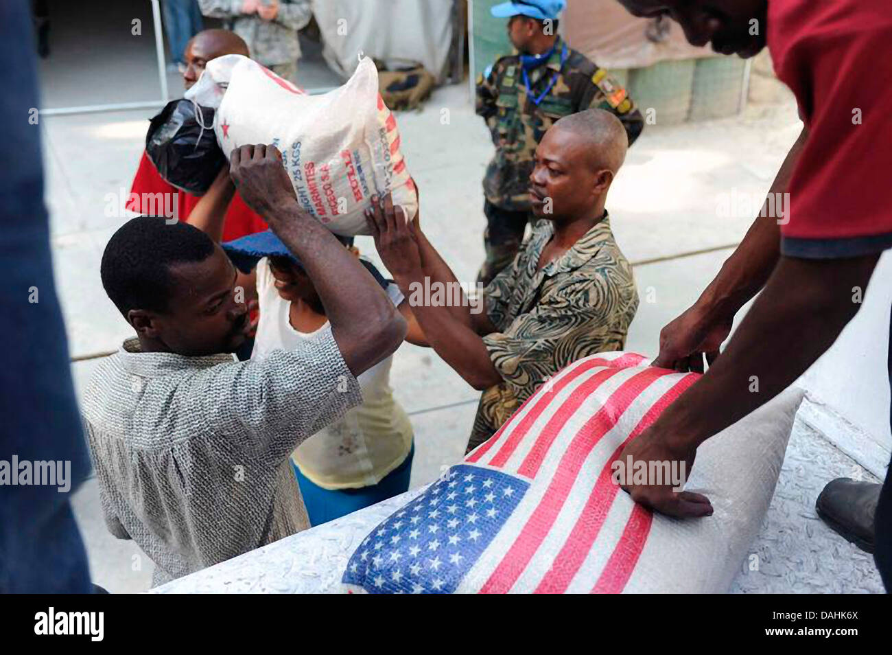 Haitians receive 25 pound bags of rice from Save the Children at an aid distribution center in the aftermath of the 7.0 magnitude earthquake that killed 220,000 people February 4, 2010 in Port-au-Prince, Haiti. Stock Photo