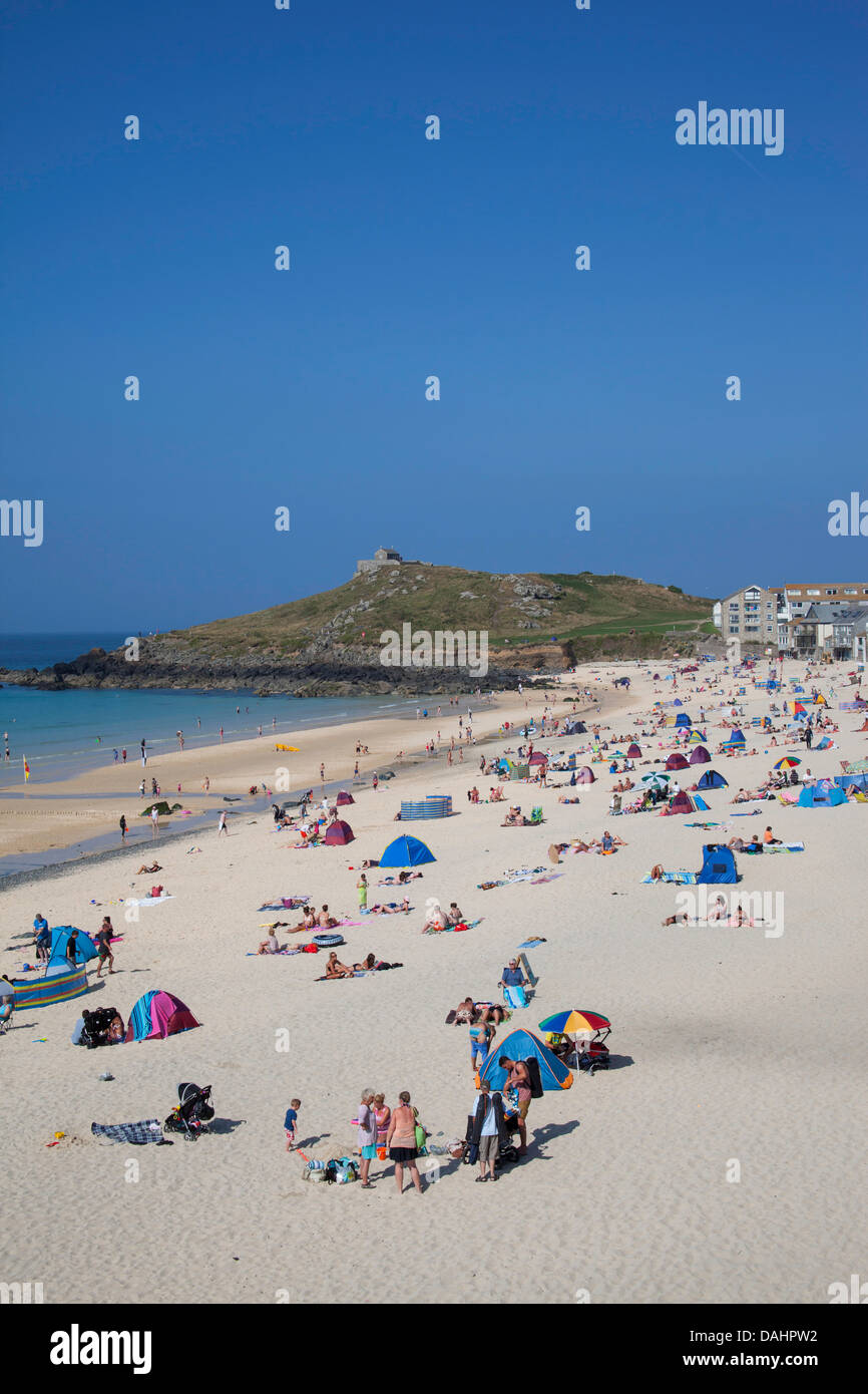 Porthmeor beach St Ives Cornwall with a view of the island.  People sunbathing on the beach in hot sunny weather. Stock Photo