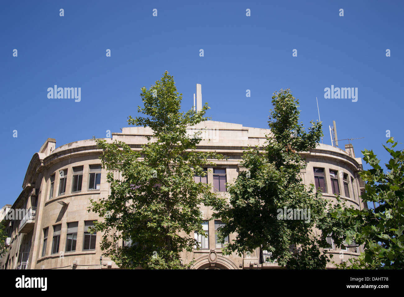 Old brick building against a clear blue sky with trees Stock Photo