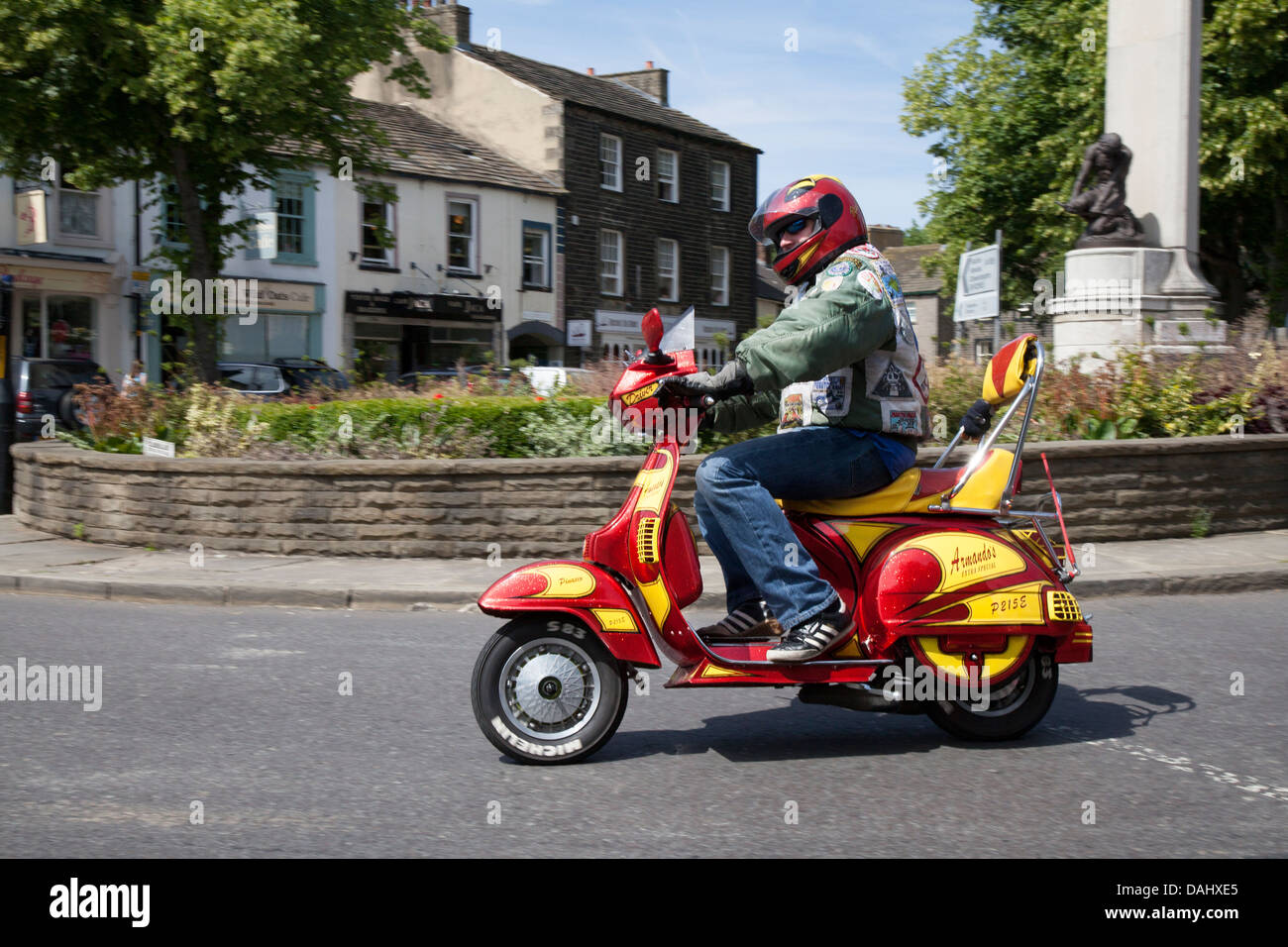 Scooter enthusiast riding his red & yellow custom red & yellow scooter. Scootering classics in the centre of Skipton, North Yorkshire, UK Stock Photo