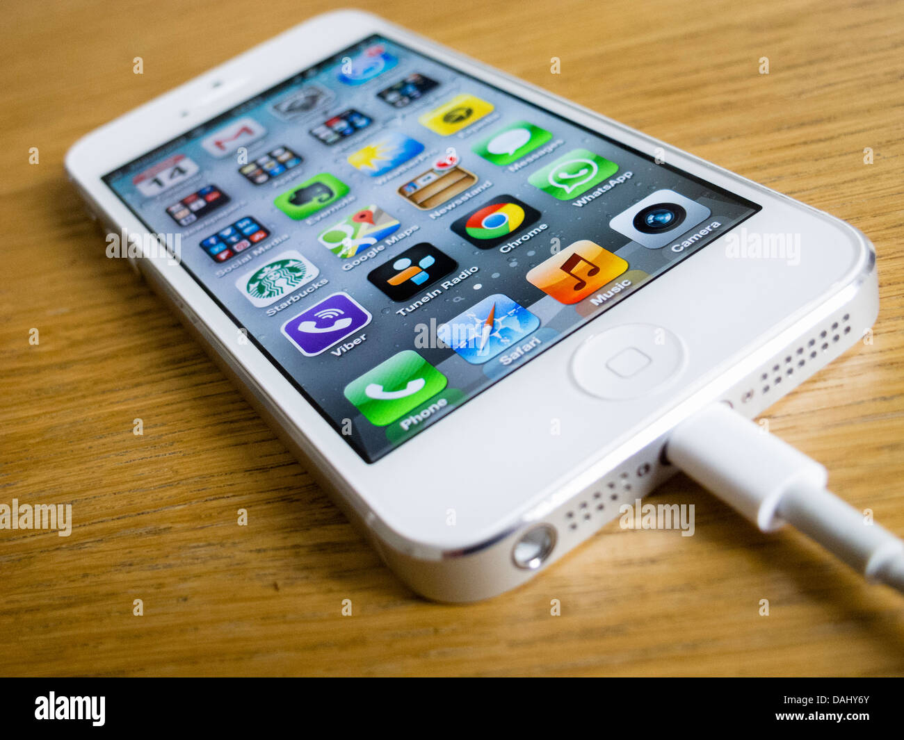 Detail of  white iPhone 5 smartphone with charger attached Stock Photo