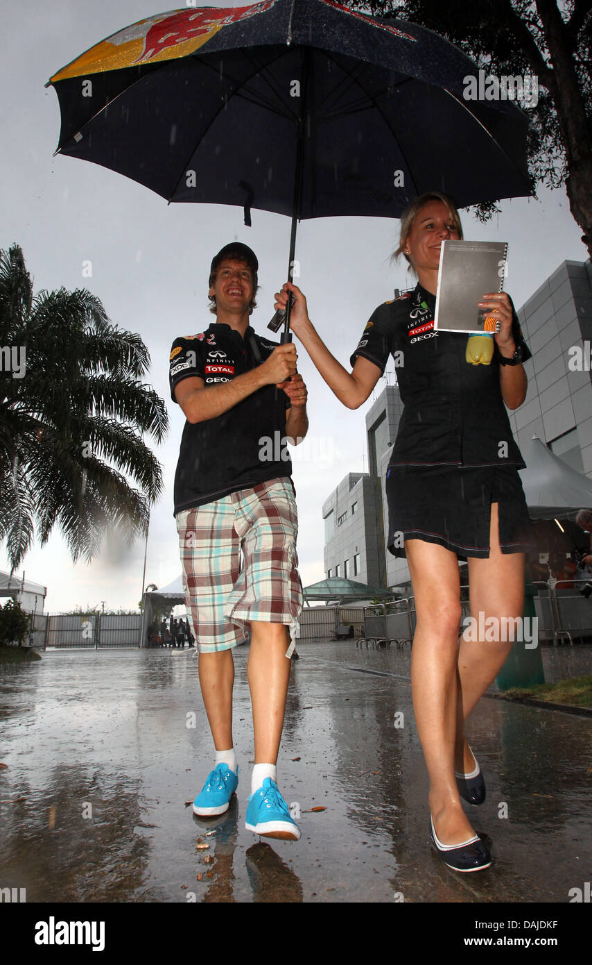 German Formula One driver Sebastian Vettel of Red Bull and his Press  Officer Britta Roeske walk under an umbrella through the paddock at the  Sepang circuit, outside Kuala Lumpur, Malaysia, 07 April