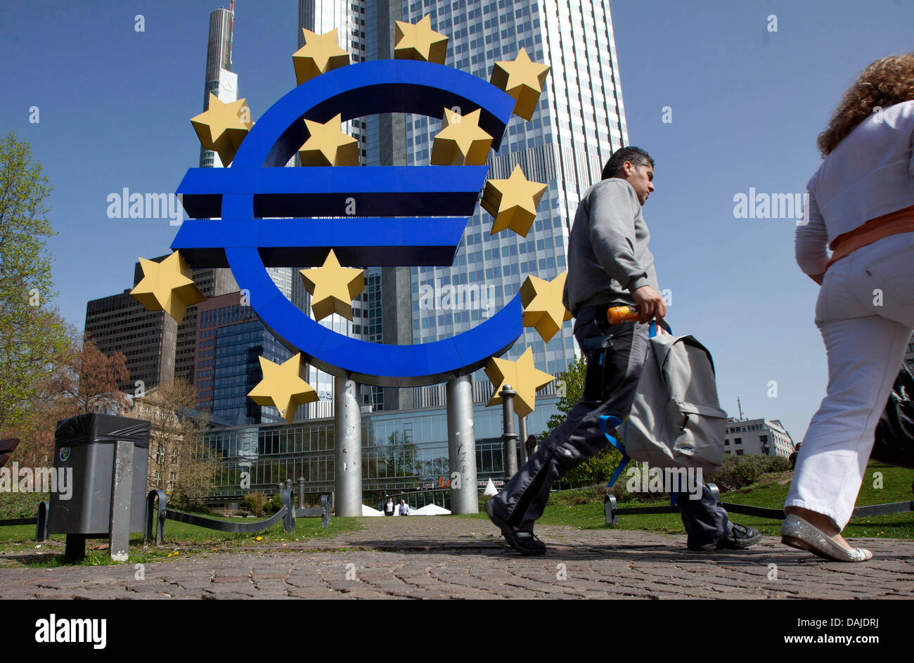 Pedestrians walk past a sculpture of the euro in front of the head office of the European Central Bank (ECB) in Frankfurt Main, Germany, 07 April 2011. The European Central Bank appears poised to deliver its first rate hike in about three years as it steps up moves to combat rising inflation. The ECB's rate-setting council's announced to raise its benchmark refinancing rate by 25 b Stock Photo