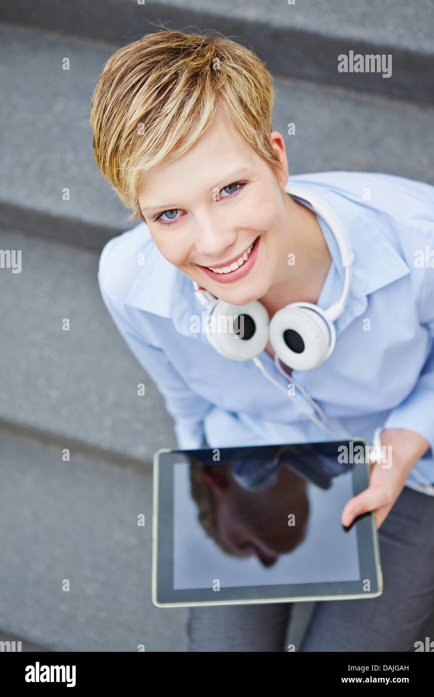 Woman with tablet computer and headphones sitting on stairs Stock Photo