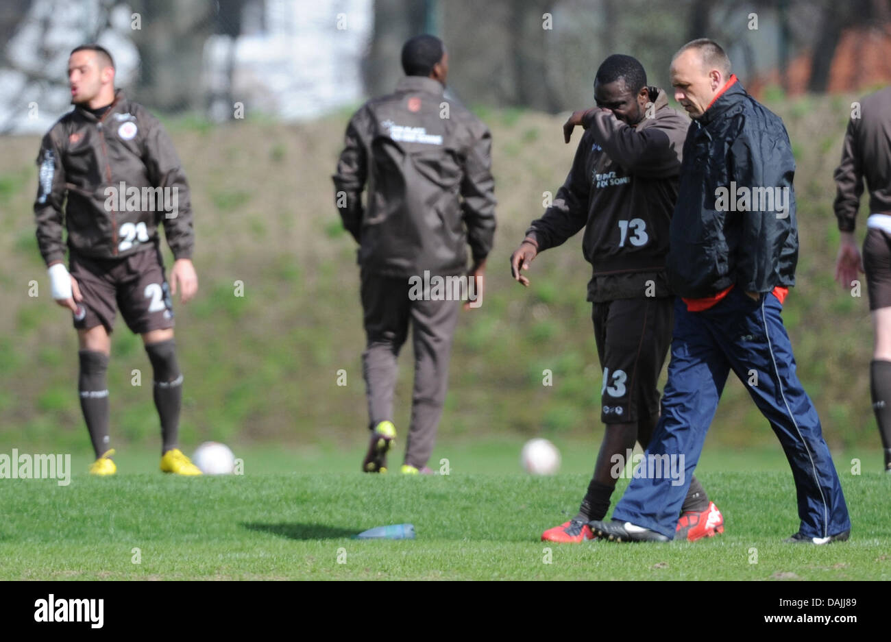 Coach Holger Stanislawski (R) speaks to striker Gerald Asamoah at the training ground in Hamburg, Germany, 13 April 2011. He is going to leave the Bundesliga football team FC St. Pauli at the end of the season. PHOTO: ANGELIKA WARMUTH Stock Photo
