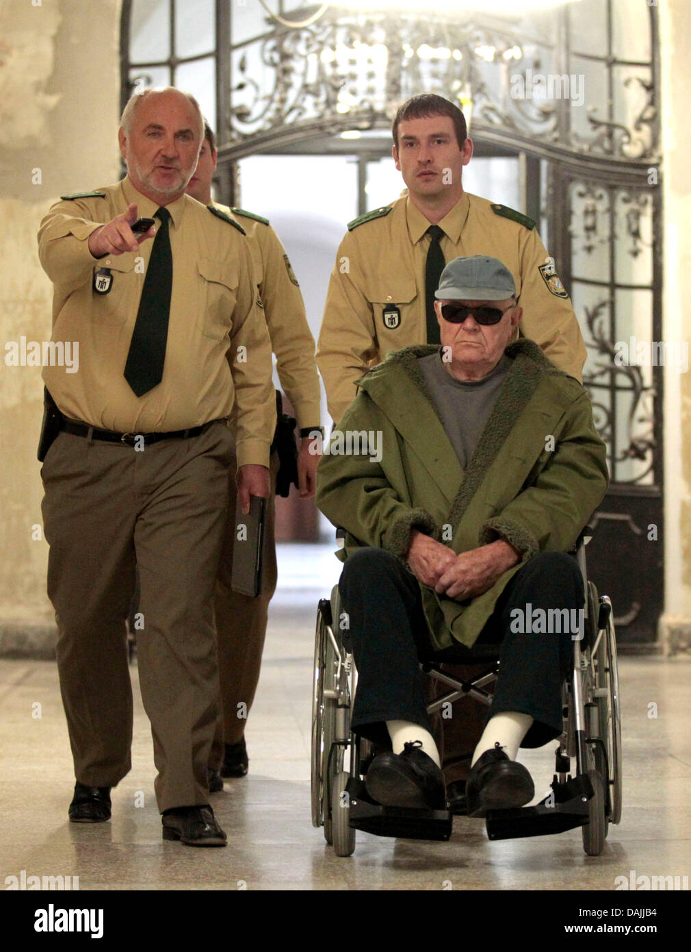Former concentration camp prisoner/guard (KAPO) John Demjanjuk is escorted to trial in a wheelchair at the state court in Munich, Germany, 14 April 2011. Demjanjuk is charged with 27,900 counts of acting as an accessory to murder, one for each person who died at Sobibor during the time he is accused of serving as a guard at the Nazi death camp. Photo: SEBASTIAN WIDMANN Stock Photo