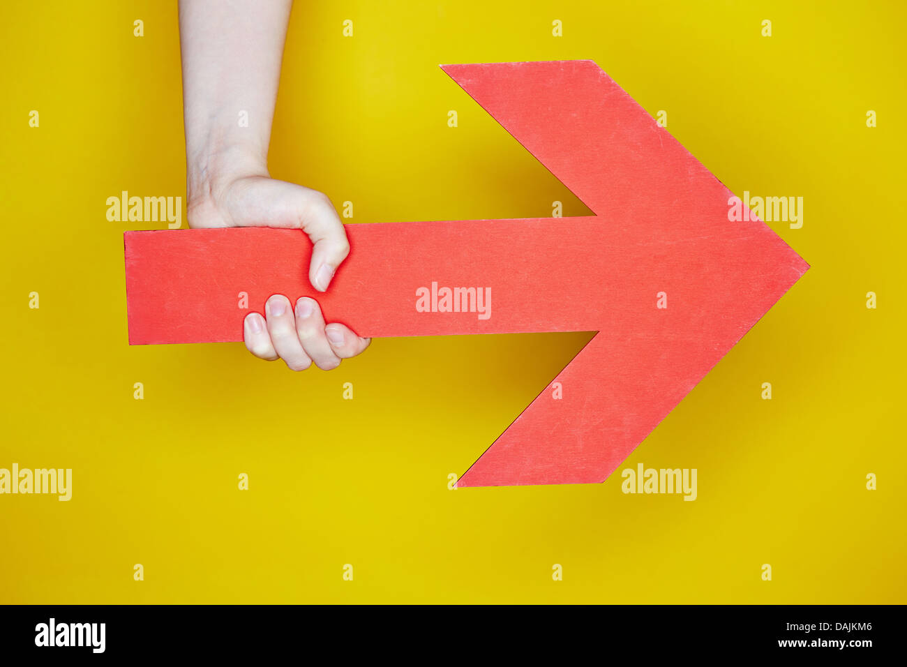 Hand holding a big red arrow pointing to the right Stock Photo - Alamy