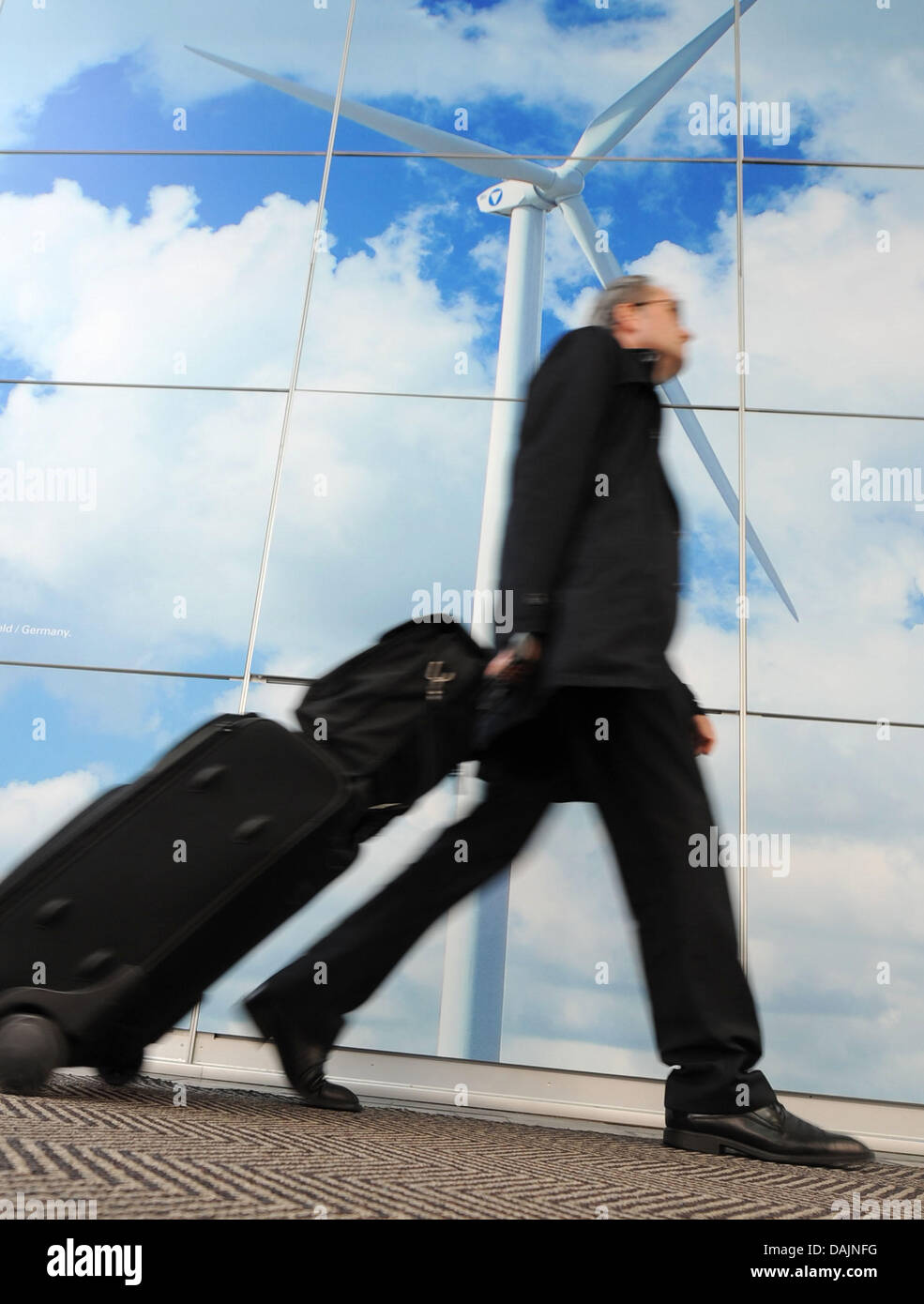 A visitor strolls past a poster of a wind turbine at the Hanover Fair in Hanover, Germany, 7 April 2011. Until 8 April, 6,500 suppliers from 65 countries present their products at the world's largest technology fair. Photo: Peter Steffen Stock Photo