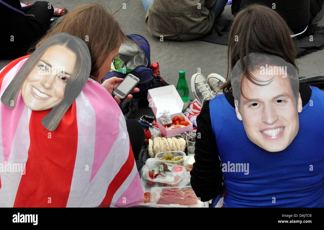 Royal fans wearing masks showing Prince William and Kate Middleton pose during the run up to the royal wedding in London, Britain, 29 April 2011. Hundreds of thousands of royalist fans and tourists are expected to line the wedding route from the Abbey to Buckingham Palace. Prince William and Kate Middleton are due to marry at Westminster Abbey, 29 April. Photo: Cordula Donhauser Stock Photo