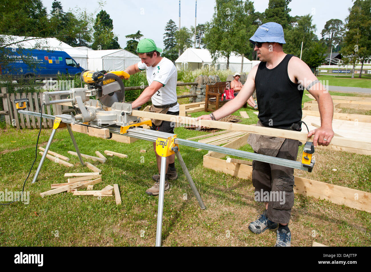 Builth Wells, Mid Wales, UK. 15th July 2013. Workmen prepare timber framed buildings. Workmen preparing The Royal Wesh Showground for the start of biggest Agricultural show in Britain next Monday 22nd July 2013 find the heat heavy going as temperatures remain above 30 degrees celsius. Photo credit: Graham M. Lawrence/Alamy Live News. Stock Photo