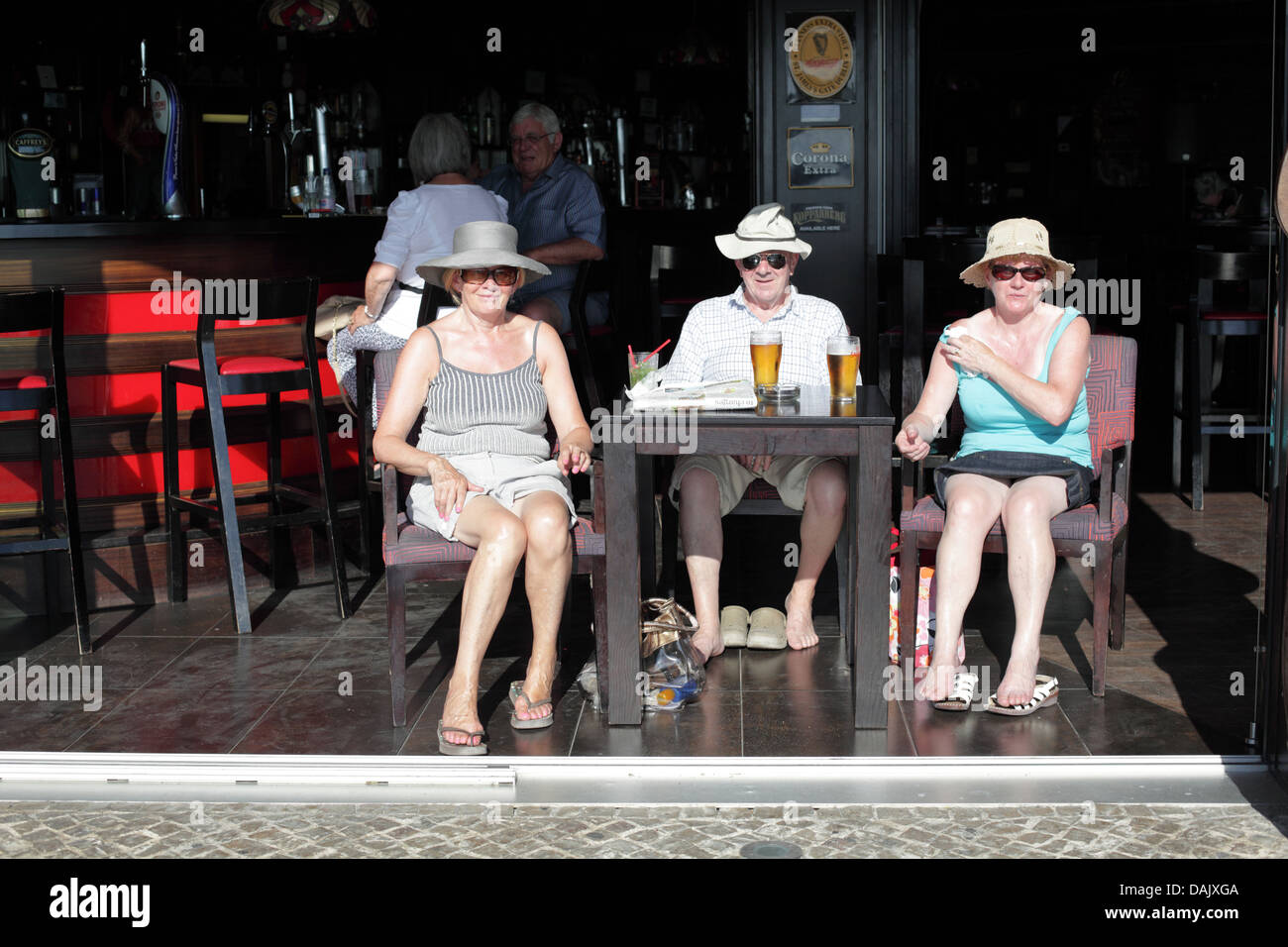 Tourists sunbathing while drinking in a bar, The Marina, Vilamoura, Algarve, Portugal. Stock Photo