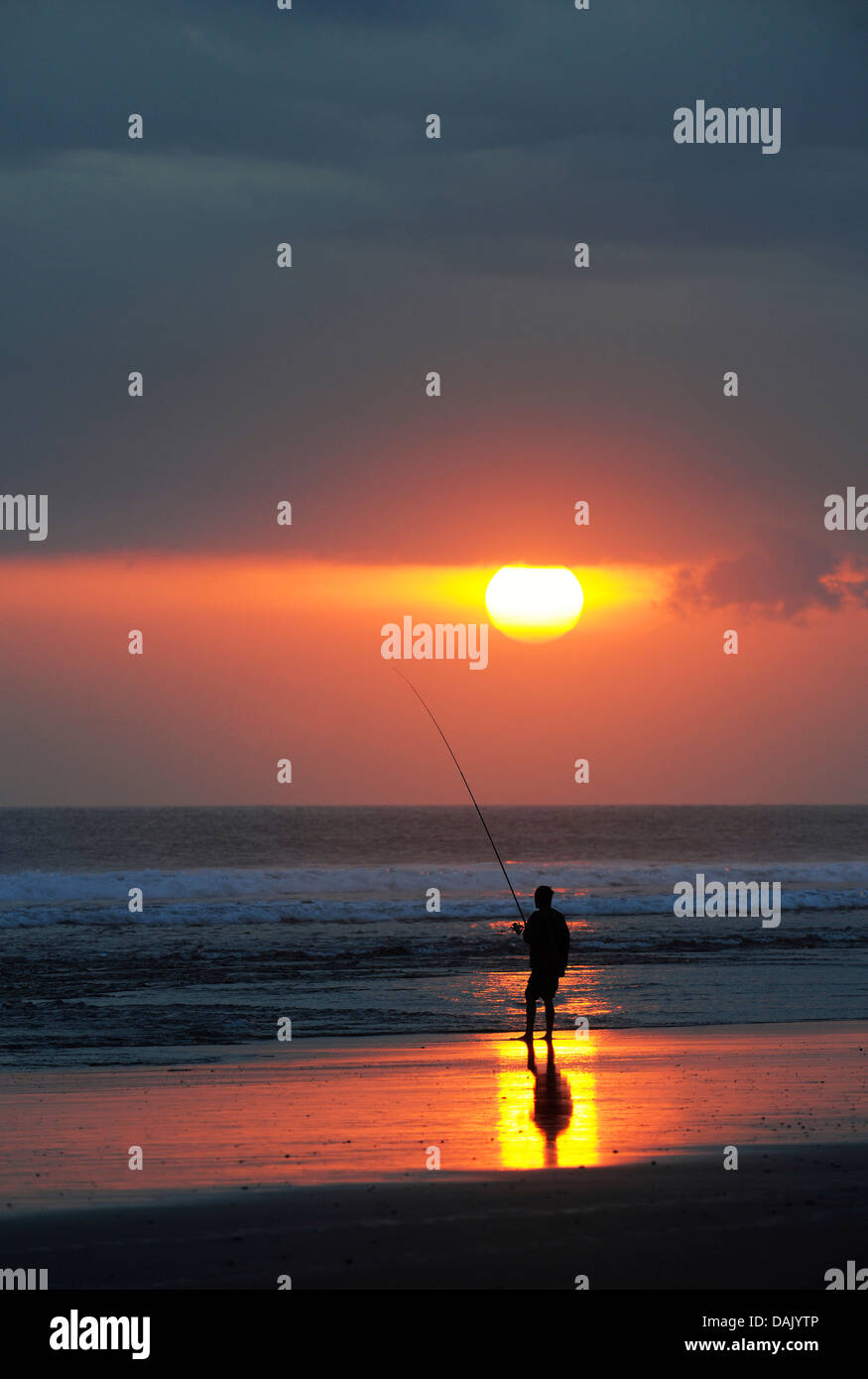Fisherman fishing at sunset on the beach Stock Photo