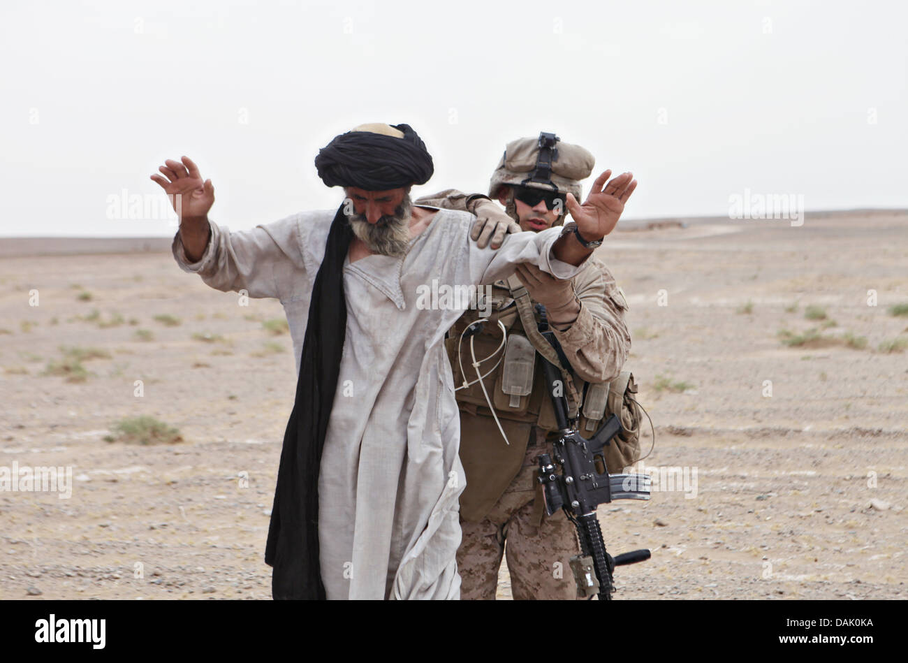 US Marine Lance Cpl. Kyle Boeck searches an elderly Afghan man at a checkpoint June 28, 2013 in Helmand Province, Afghanistan. Stock Photo