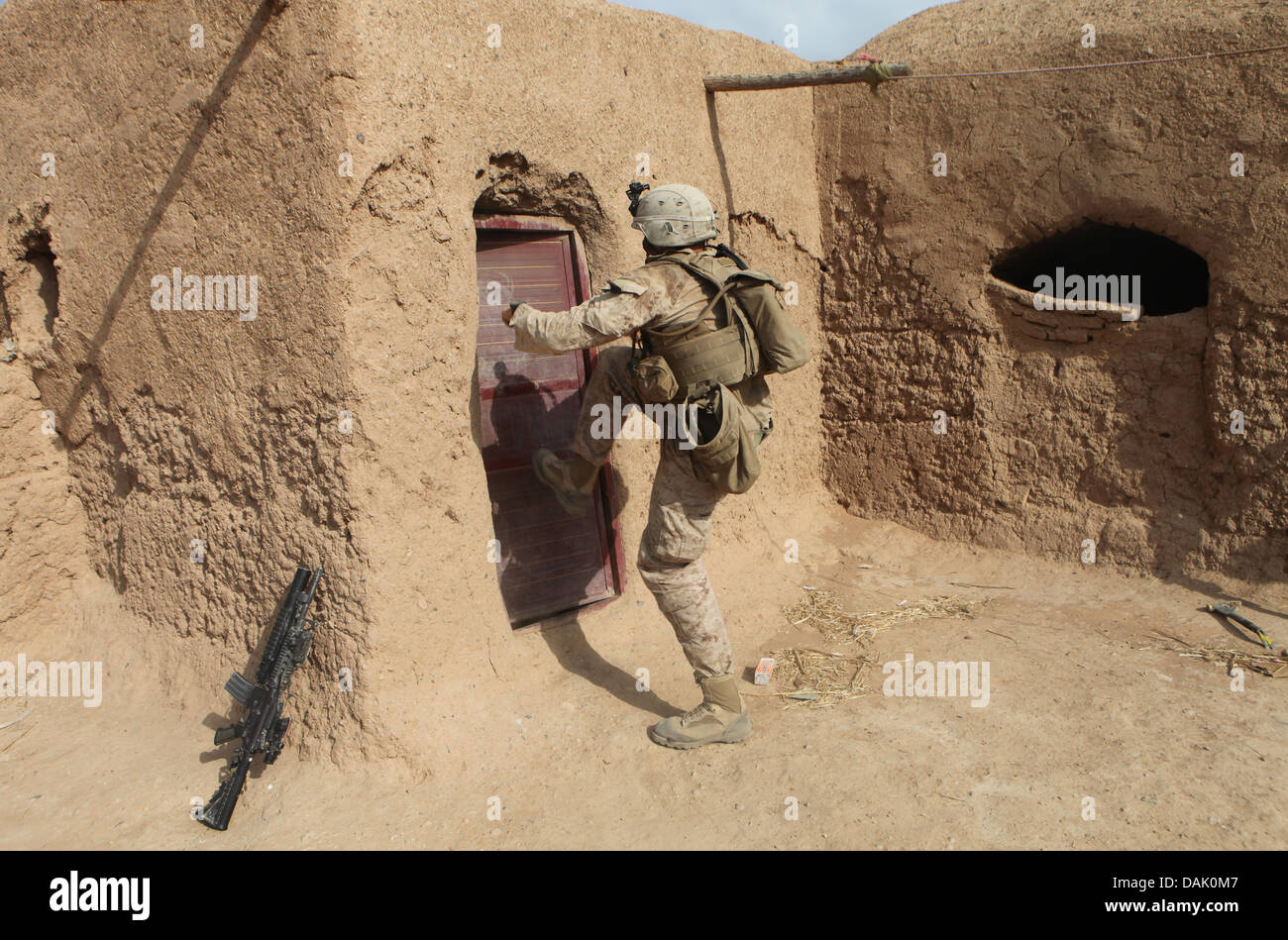 US Marine Lance Cpl. Christopher Ward kicks in a locked door during a search for insurgents at a compound June 30, 2013 in Helmand Province, Afghanistan. Stock Photo
