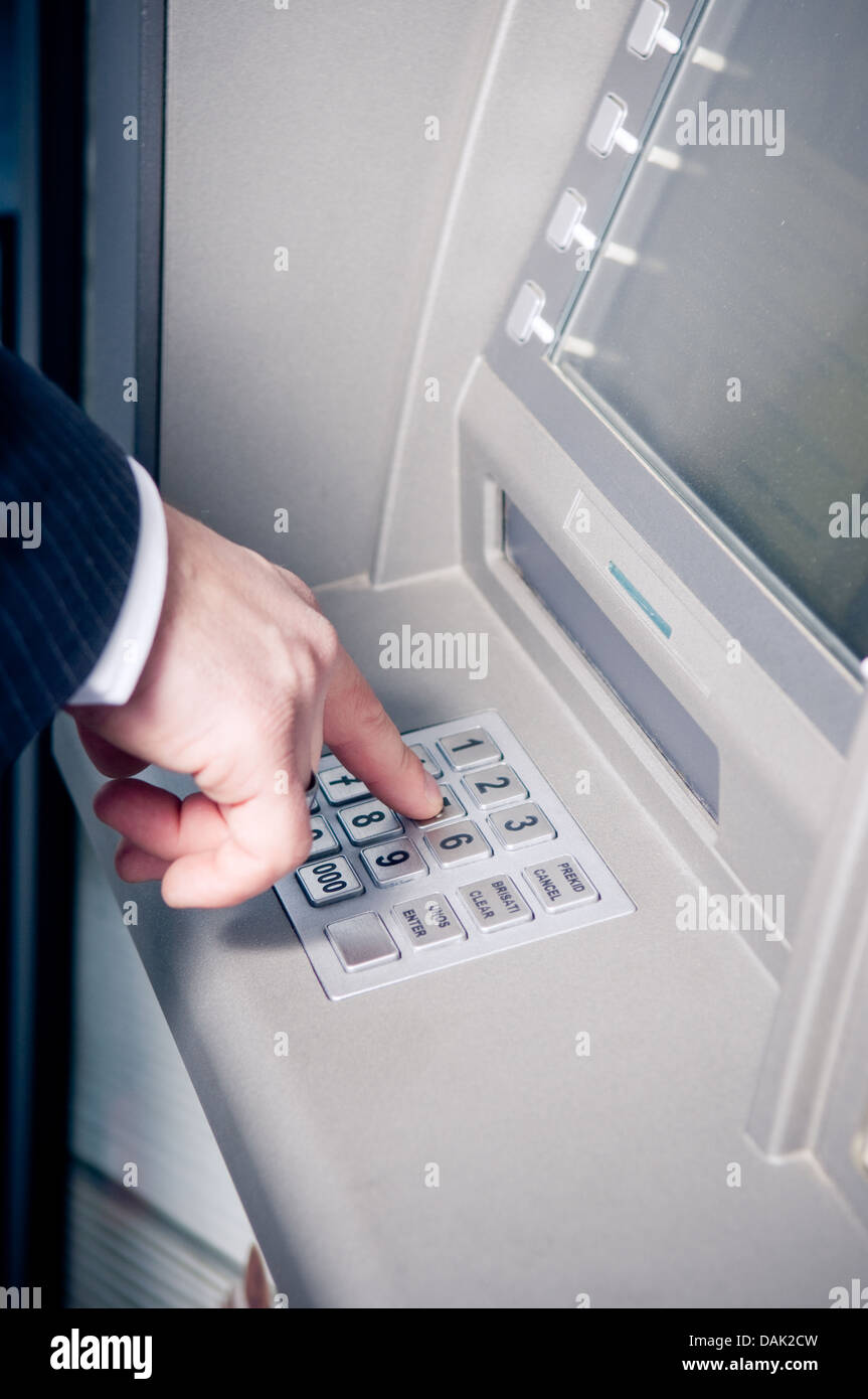 Businessman using atm to withdraw cash Stock Photo