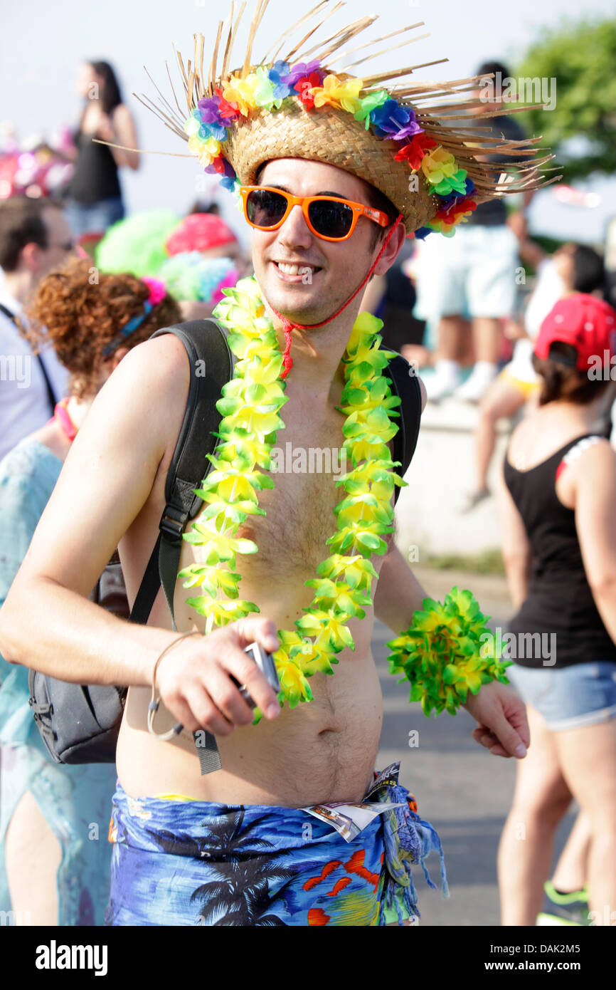 Happy cool young guy with sunglasses, colourful flower hat and necklace posing during Lake Parade street event in Geneva, Switzerland on sunny summer day. Participants expressing happiness, enjoyment, fun, freedom, love. Credit:  ImageNature, Alexander Belokurov / Alamy Stock Photo