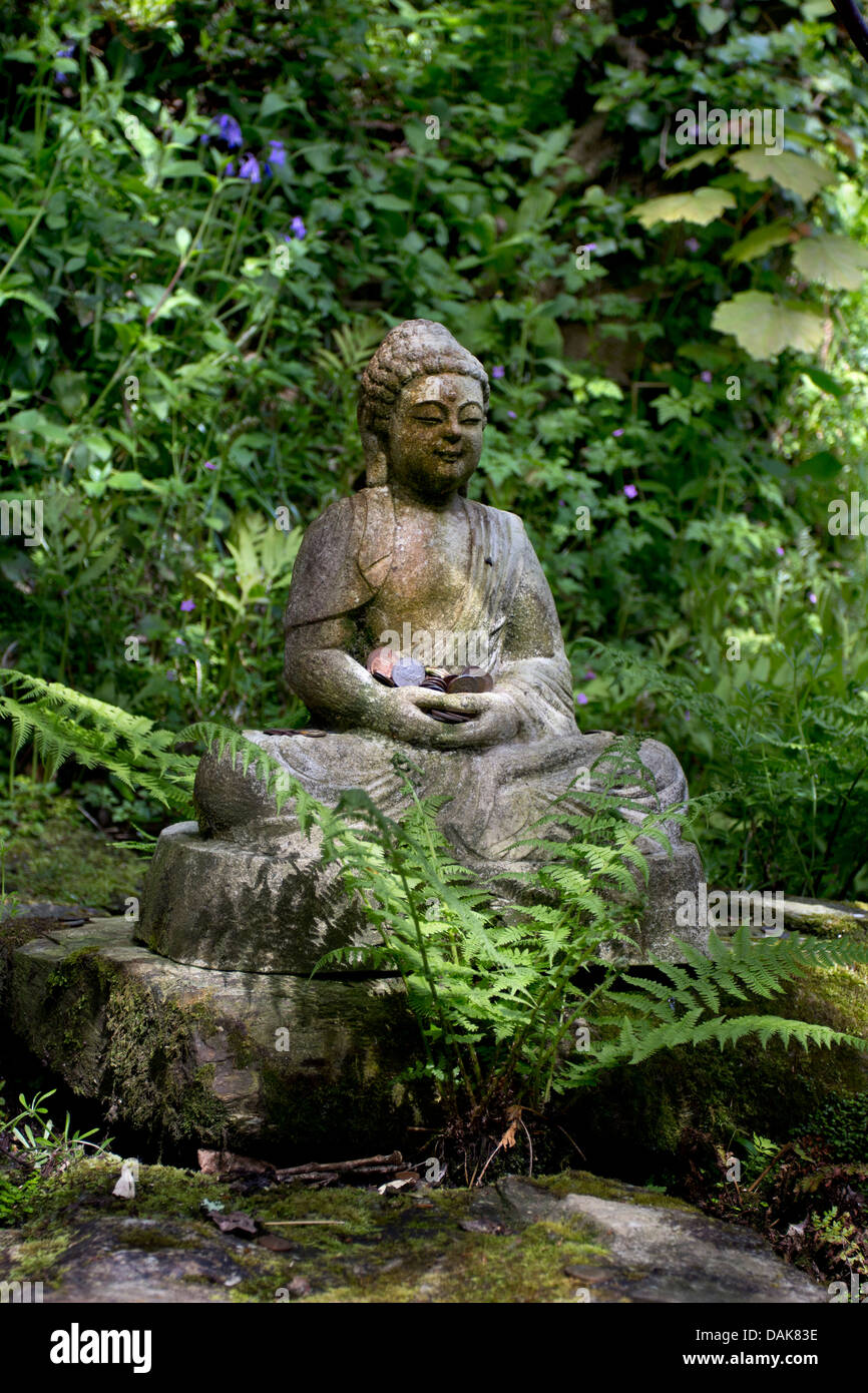 Sitting Buddha statue in a shaded spot in the garden Stock Photo Alamy