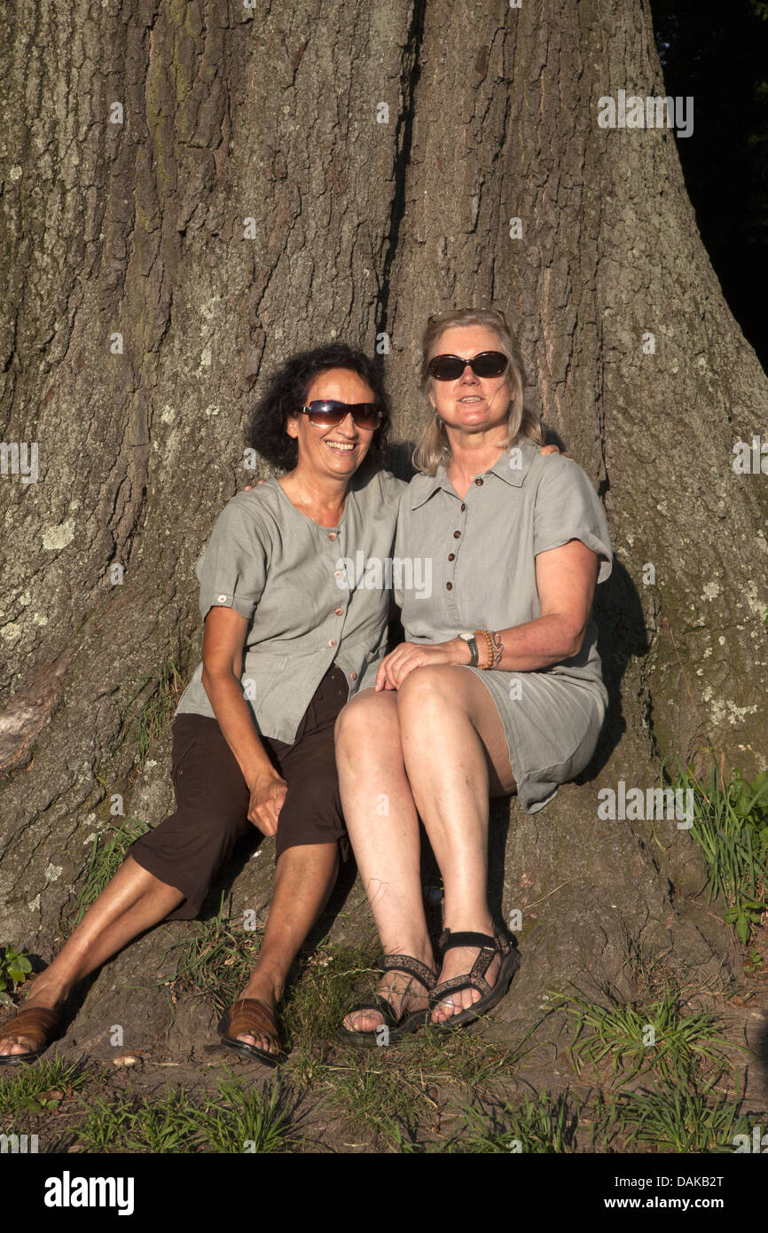 Two sixty something year old friends pose together for a photo in Prospect Park, Brooklyn, NY. Same age children. Stock Photo